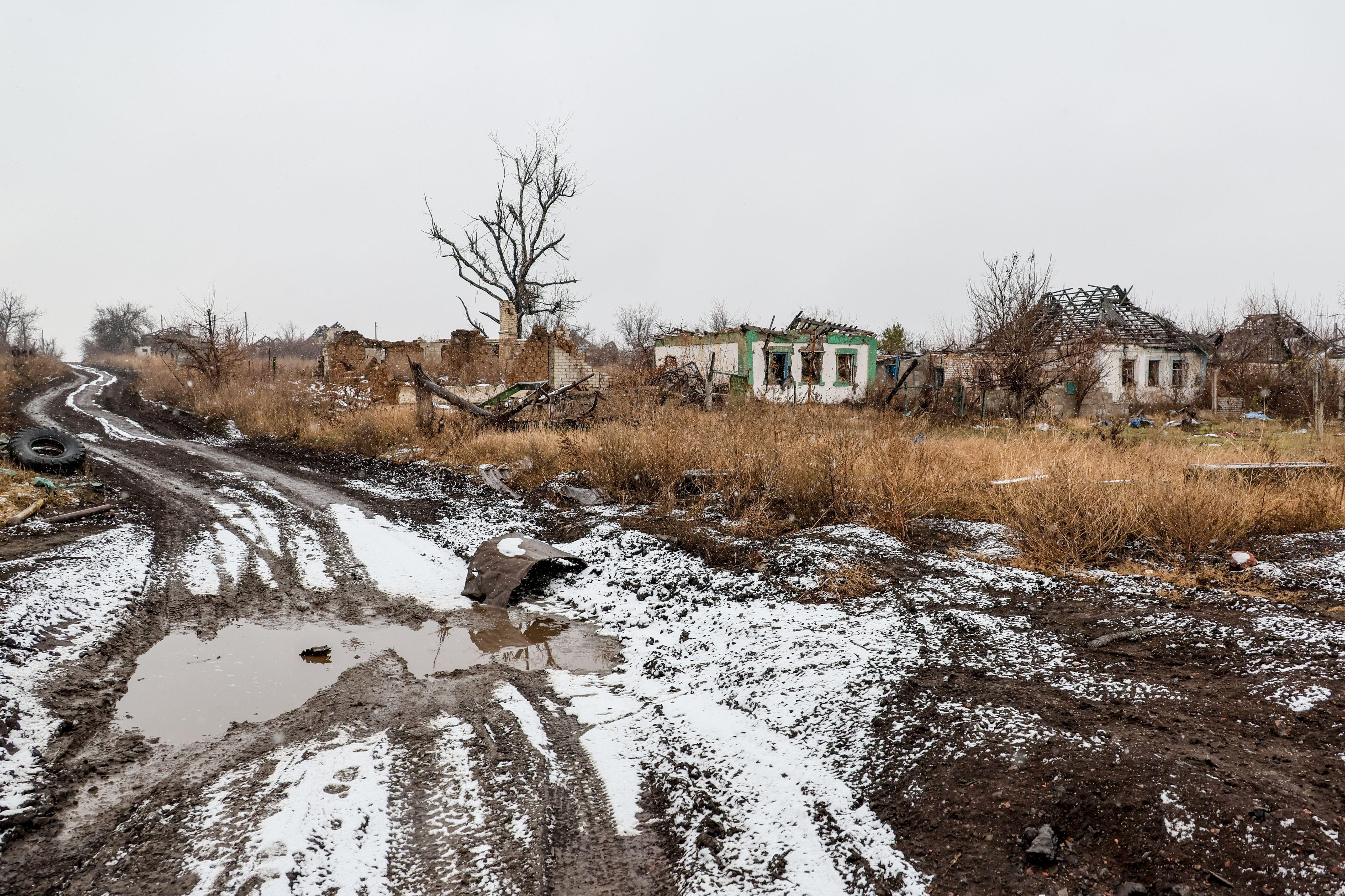 Schlammige, schneebedeckte Straße mit zerstörten Häusern