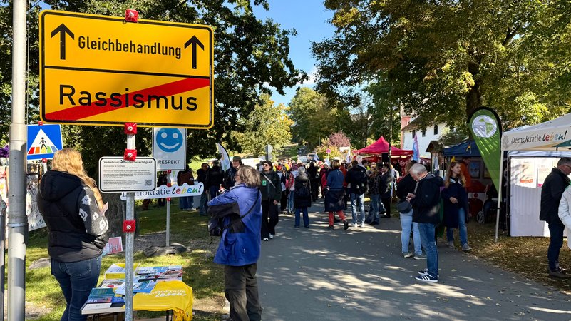 Auf einem selbstgemachten Ortsschild ist das Wort "Rassismus" durchgestrichen und der Weg führt Richtung "Gleichbehandlung". | Bild: BR/ Lasse Berger Auf einem selbstgemachten Ortsschild ist das Wort "Rassismus" durchgestrichen und der Weg führt Richtung "Gleichbehandlung".