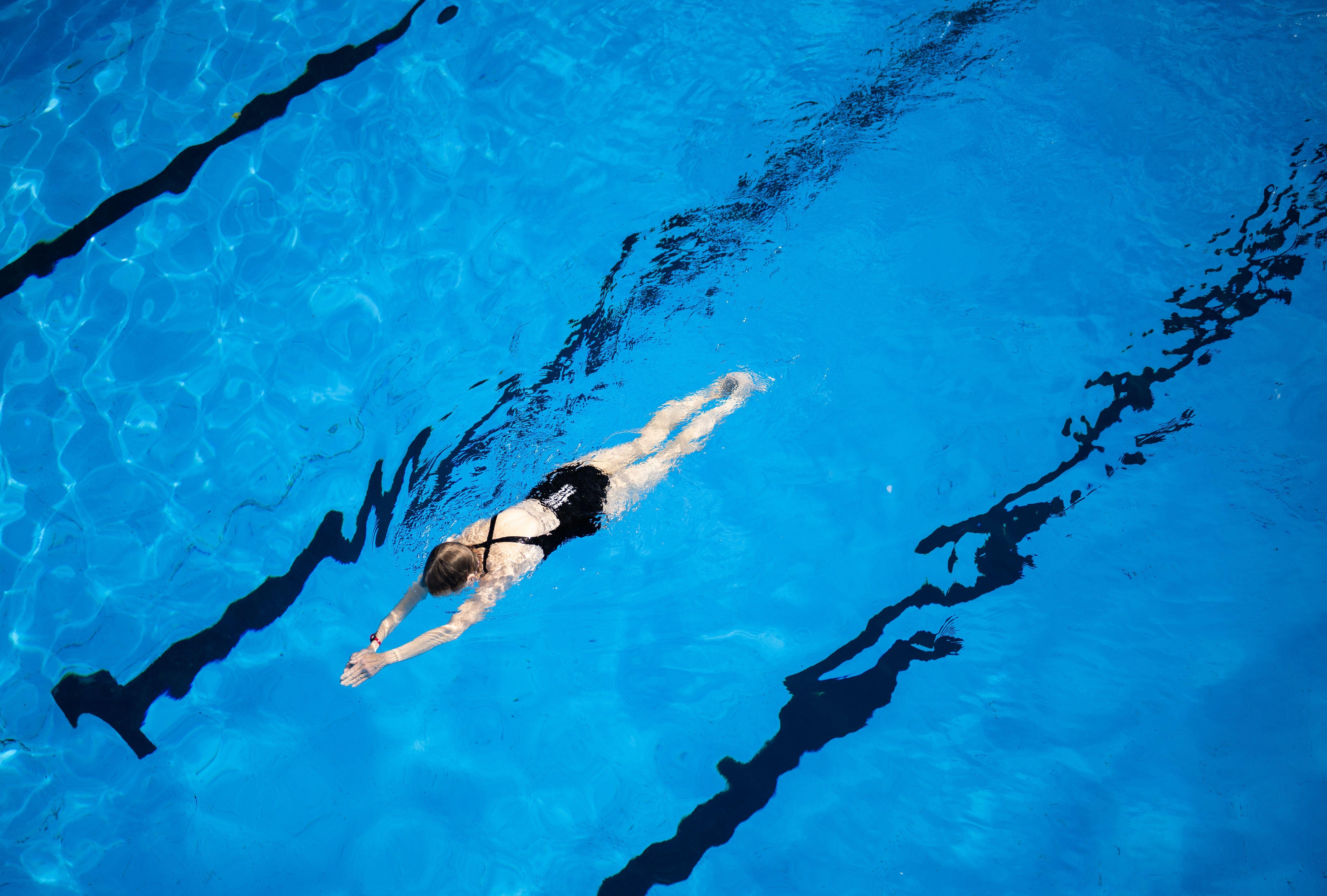 Eine Frau schwimmt in einem Freibadbecken.
