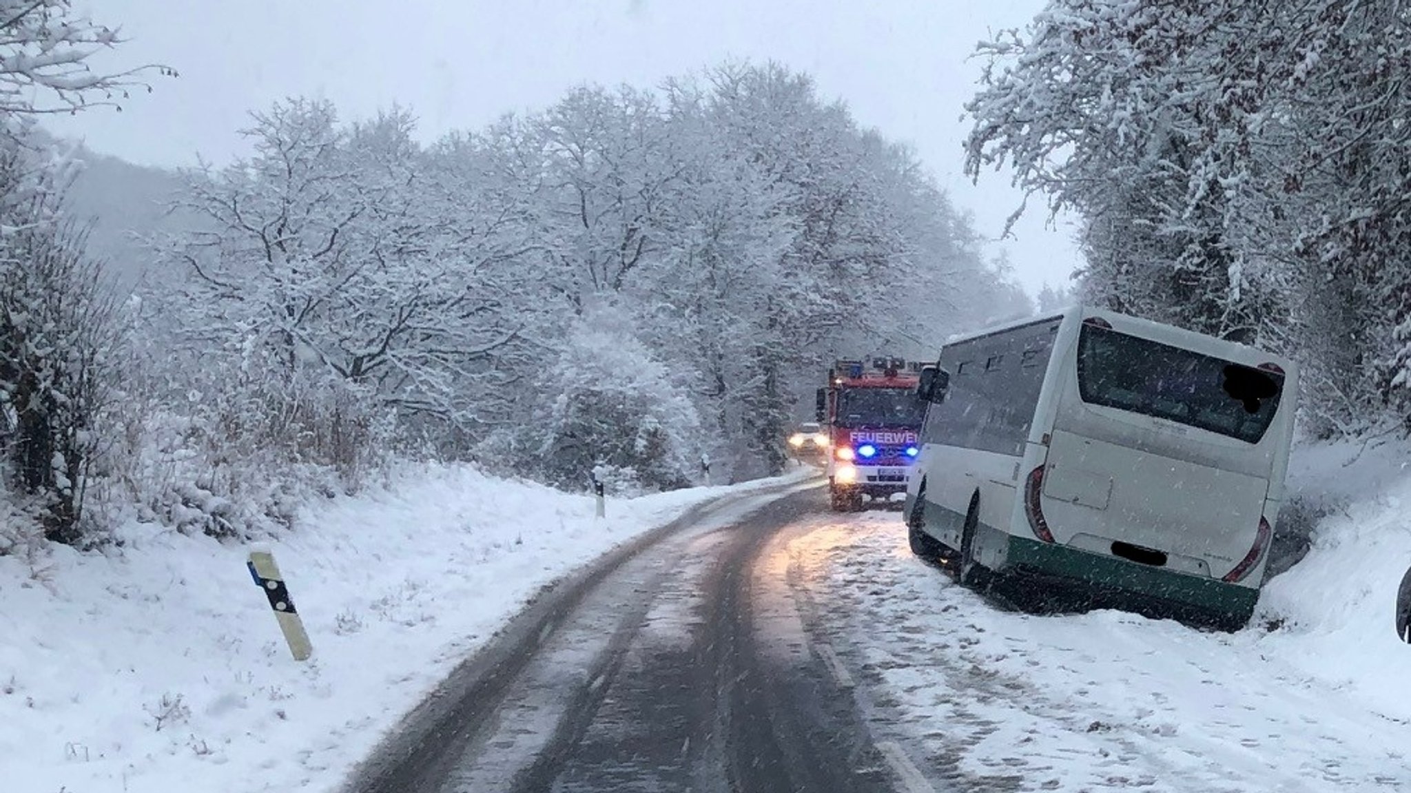 Bus auf schneebedeckter Fahrbahn im Seitengraben