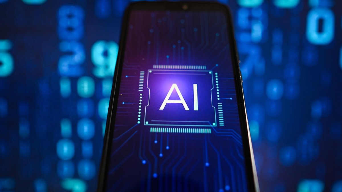 In this photo illustration artificial intelligence (AI) logo is displayed on a smartphone with coding on the background. 