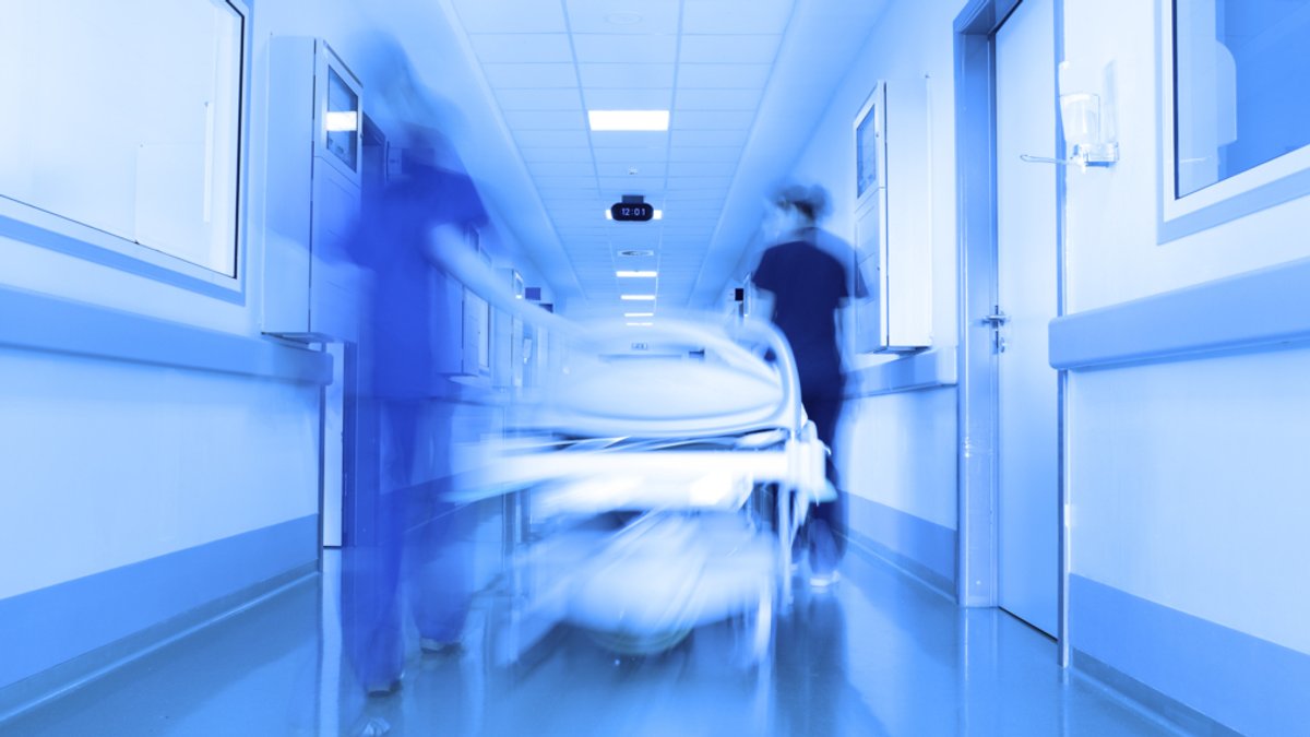 Ein Krankenbett wird durch einen Gang im Krankenhaus geschoben.