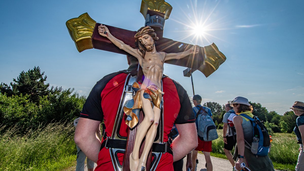 Ein Pilger trägt während der größten Fußwallfahrt Deutschlands ein Holzkreuz