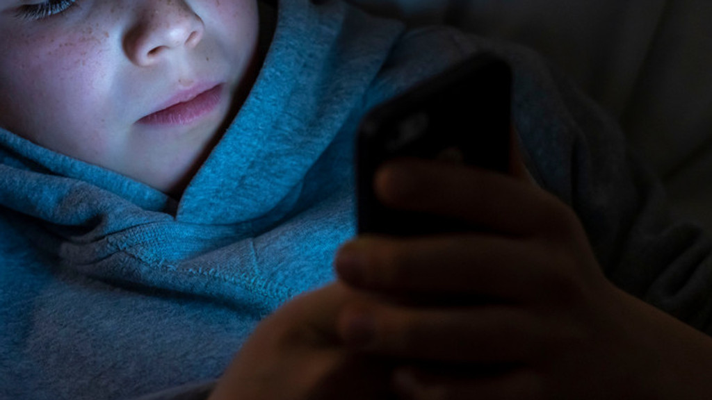 Junge mit Smartphone im Bett (Symbolbild)