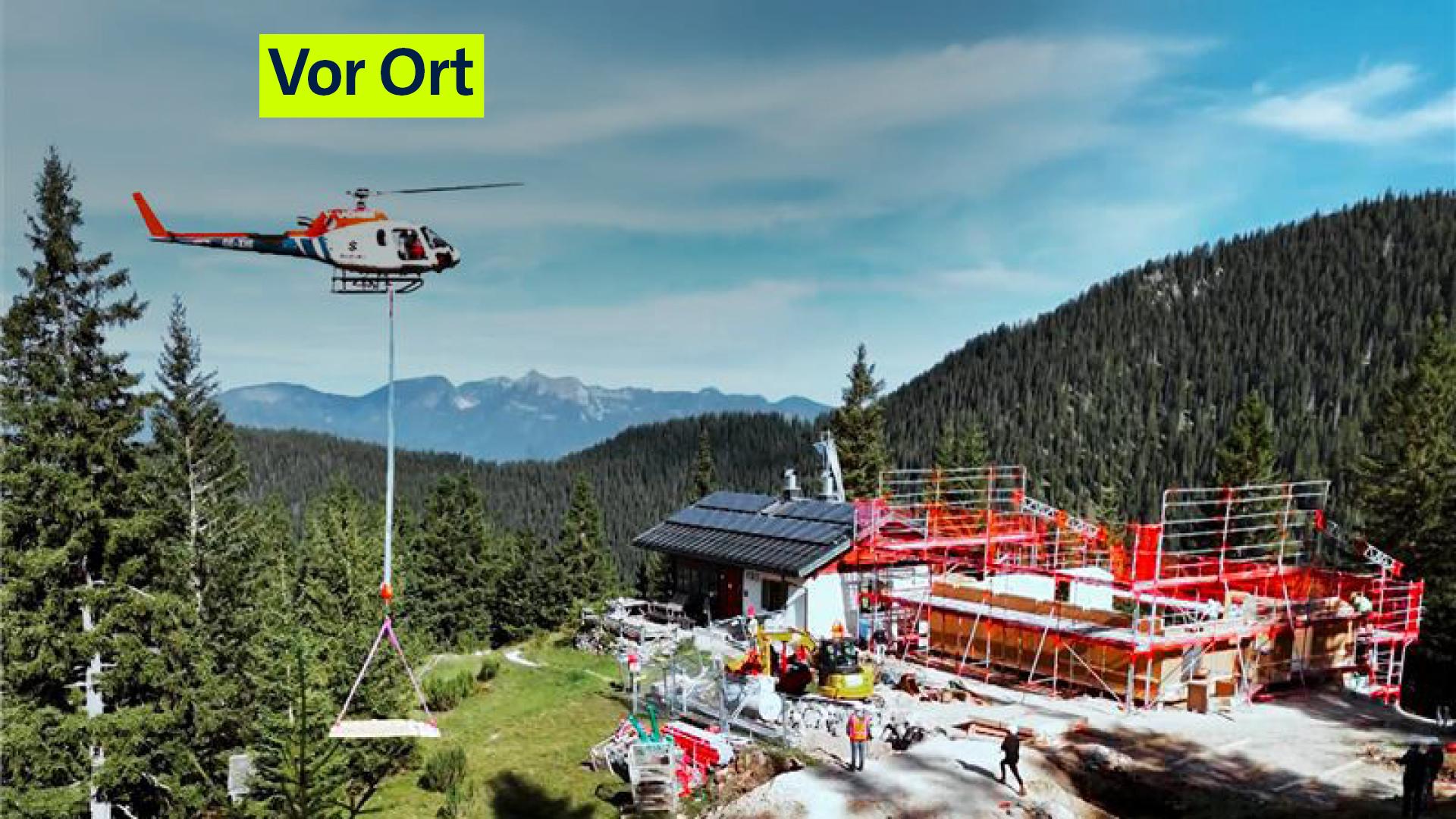 Blick auf die Baustelle mit Hubschrauber und Bauleuten.