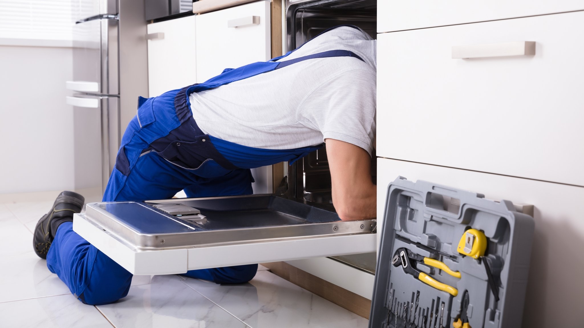 Ein Handwerker repariert eine Geschirrspülmaschine (Symbolbild). | Bild: BR/stock.adobe.com/Andrey Popov Ein Handwerker repariert eine Geschirrspülmaschine (Symbolbild).