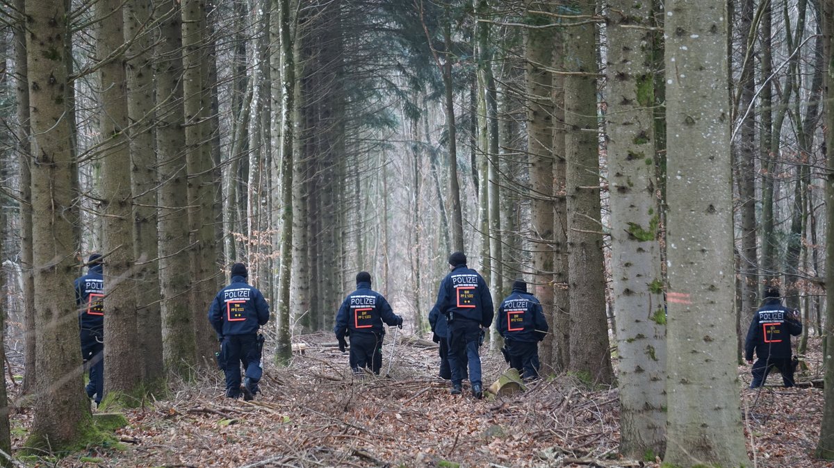 Polizisten durchkämmen ein Waldgebiet auf der Suche nach einer vermissten Person.