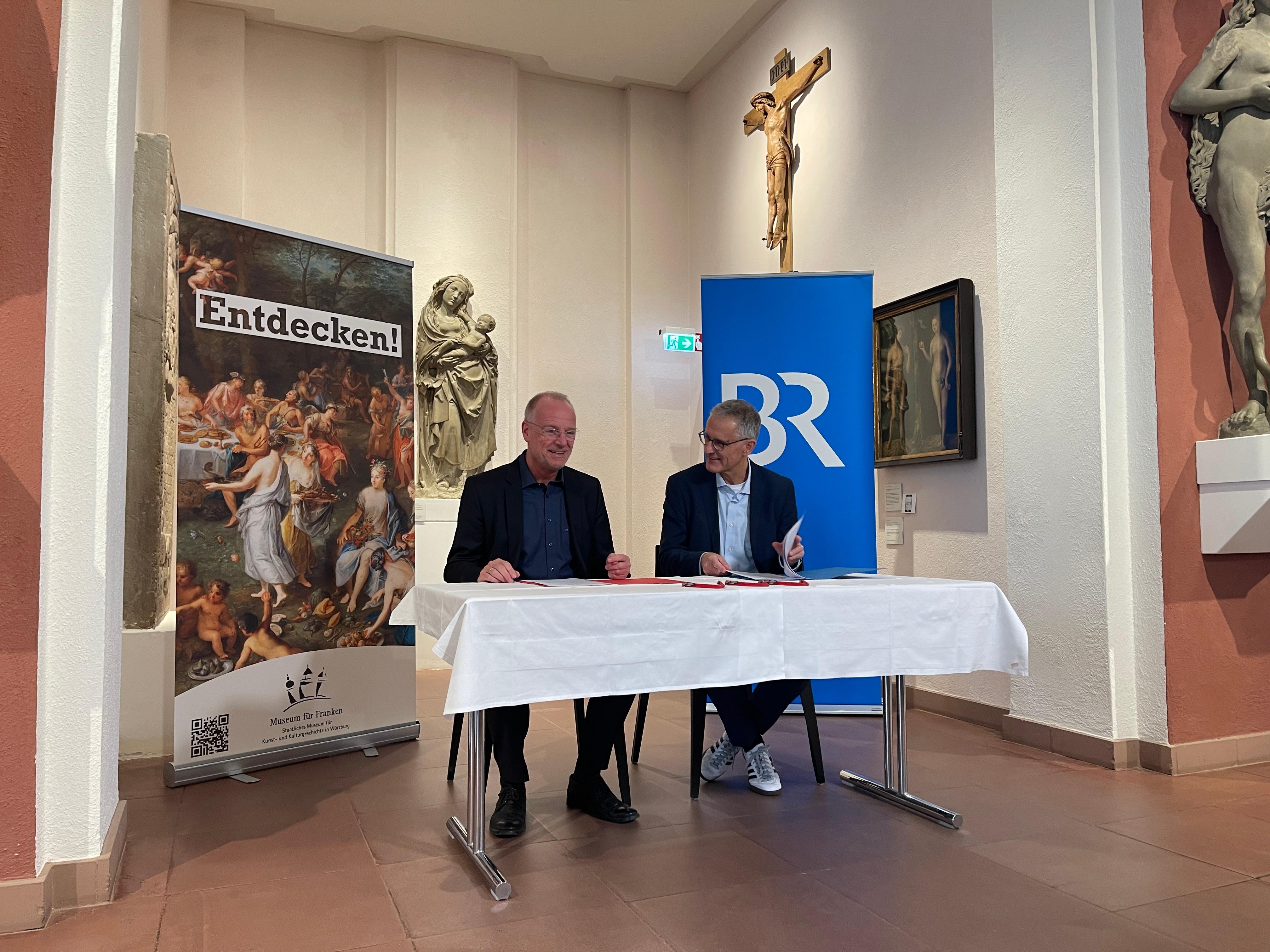 Jörg Meißner (links) und Tassilo Forchheimer (rechts) unterschreiben den Kulturpartnerschaftsvertrag im Museum für Franken