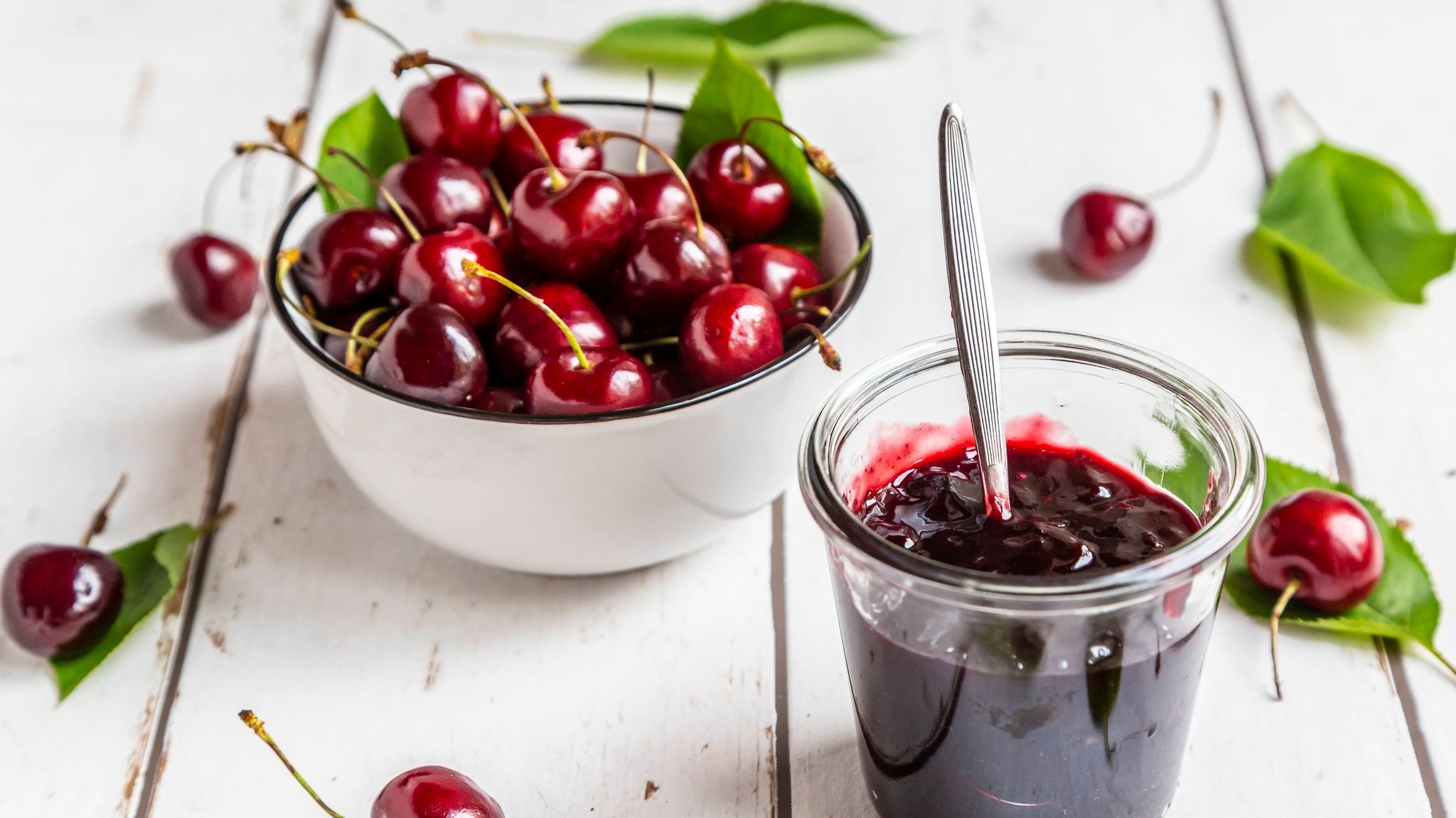 Kirschen und ein offenes Glas mit Kirschkonfitüre.