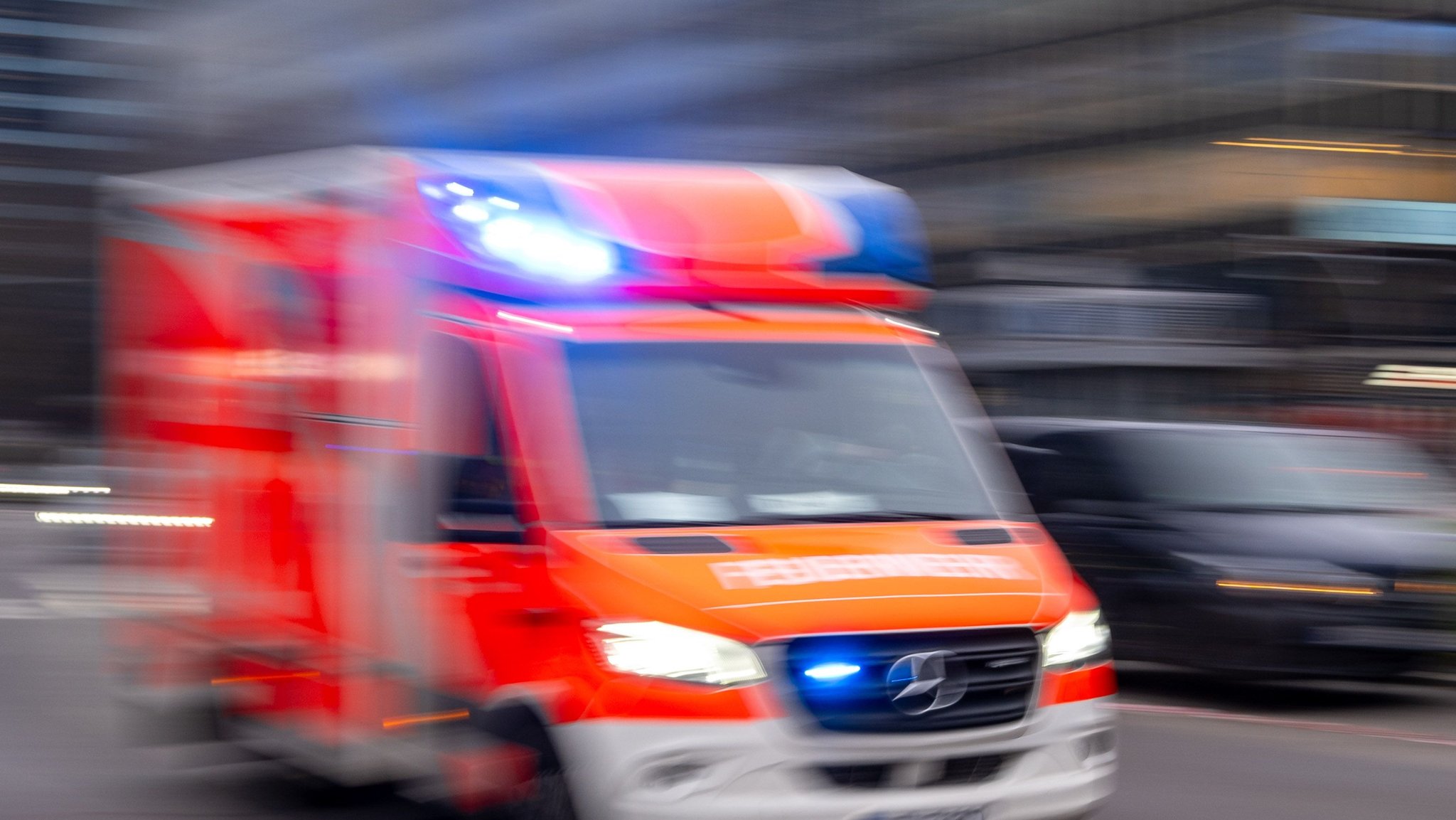 Ein Rettungswagen der Feuerwehr fährt mit Blaulicht auf einer Straße. 