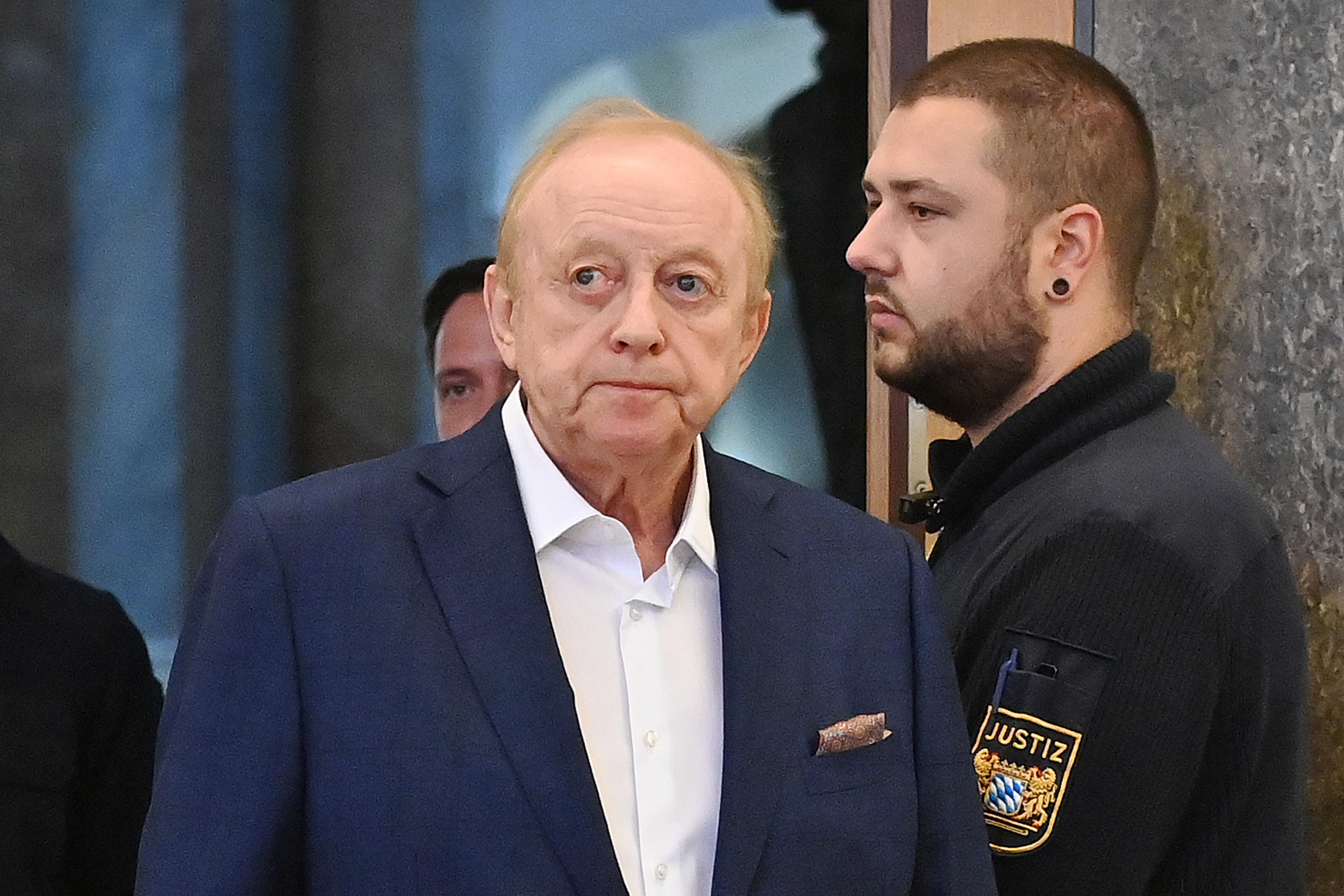 Alfons Schuhbeck geht an einem Justizbeamten vorbei