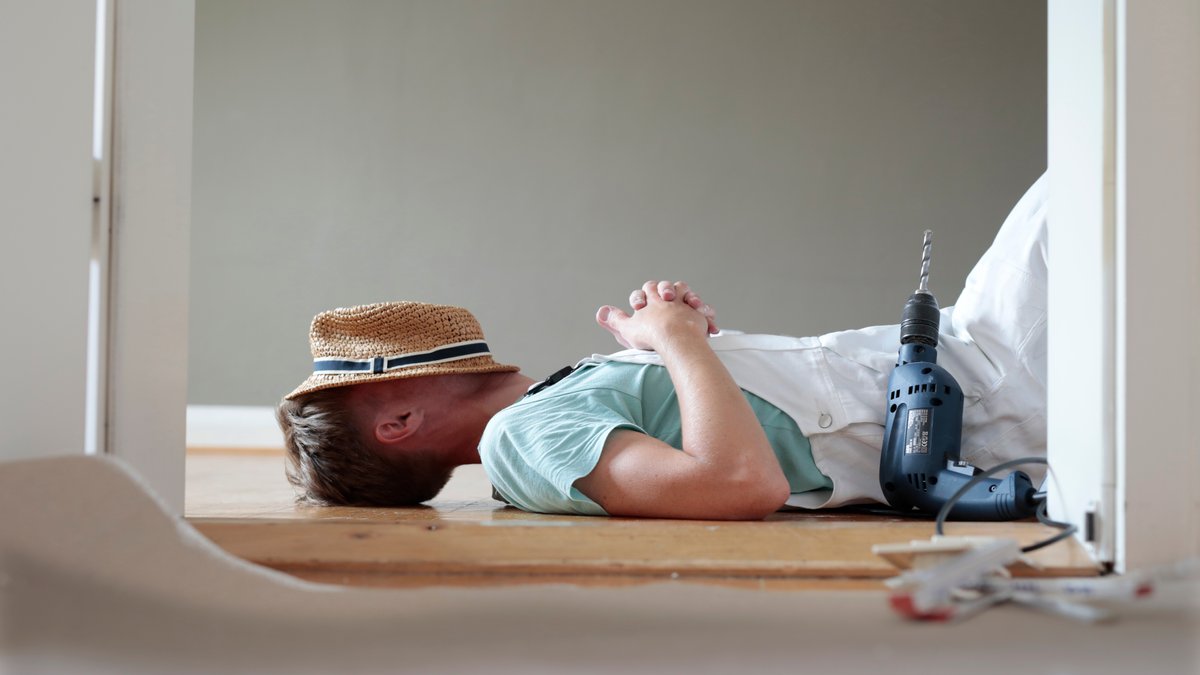 Gestelltes Foto: Handwerker mit Hut hält ein Mittagsschläfchen