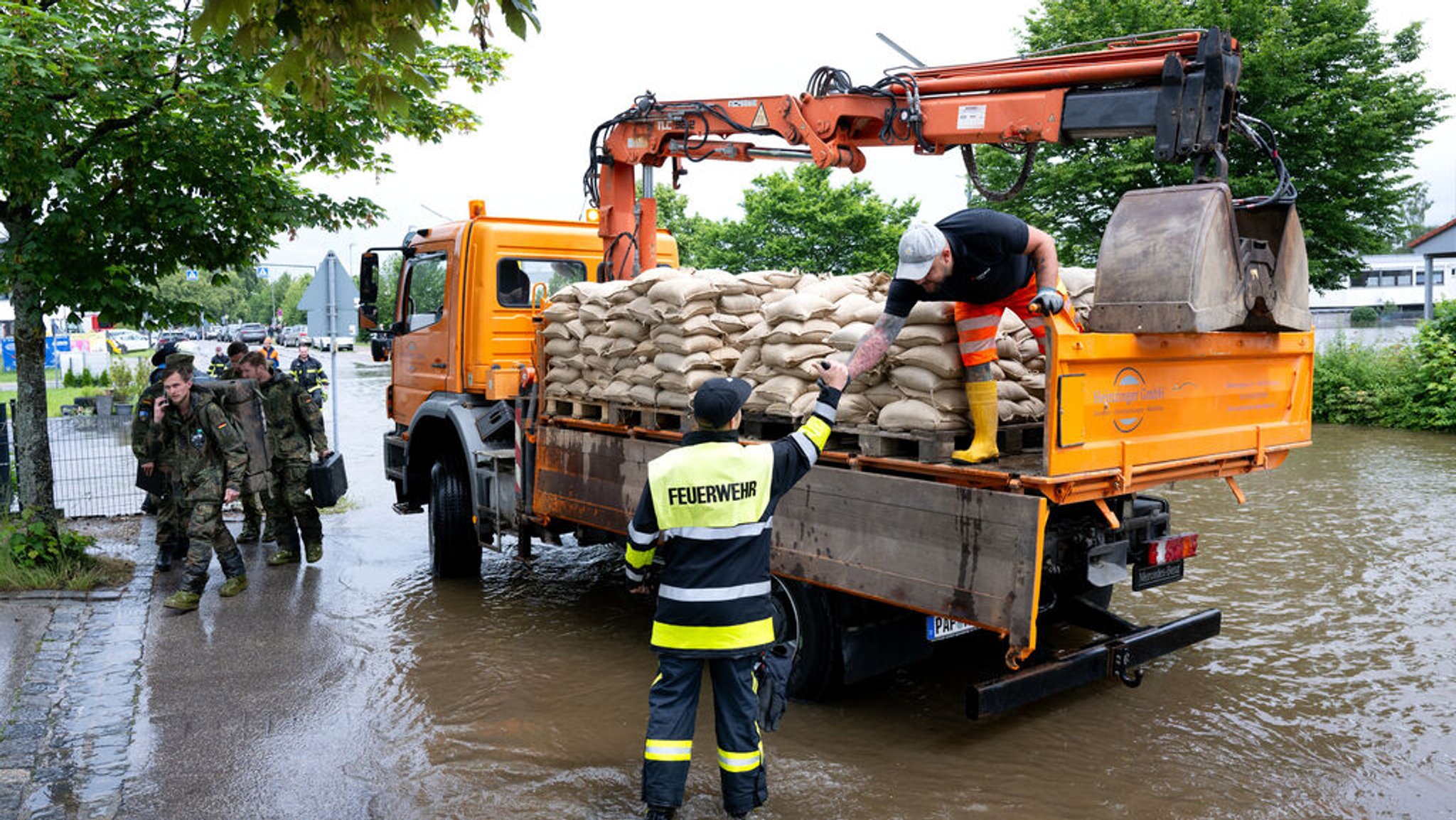 ARCHIV - 02.06.2024, Bayern, Reichertshofen: Helfer bringen Sandsäcke zu einer überfluteten Straße im bayerischen Reichertshofen. Nach tagelangem Dauerregen treten im Süden Deutschlands Flüsse und Bäche über die Ufer. Rund 40.000 Einsatzkräfte sind allein in Bayern unterwegs.  (zu dpa: «Die wichtigsten Ereignisse des Jahres 2024 - Juni») Foto: Sven Hoppe/dpa +++ dpa-Bildfunk +++