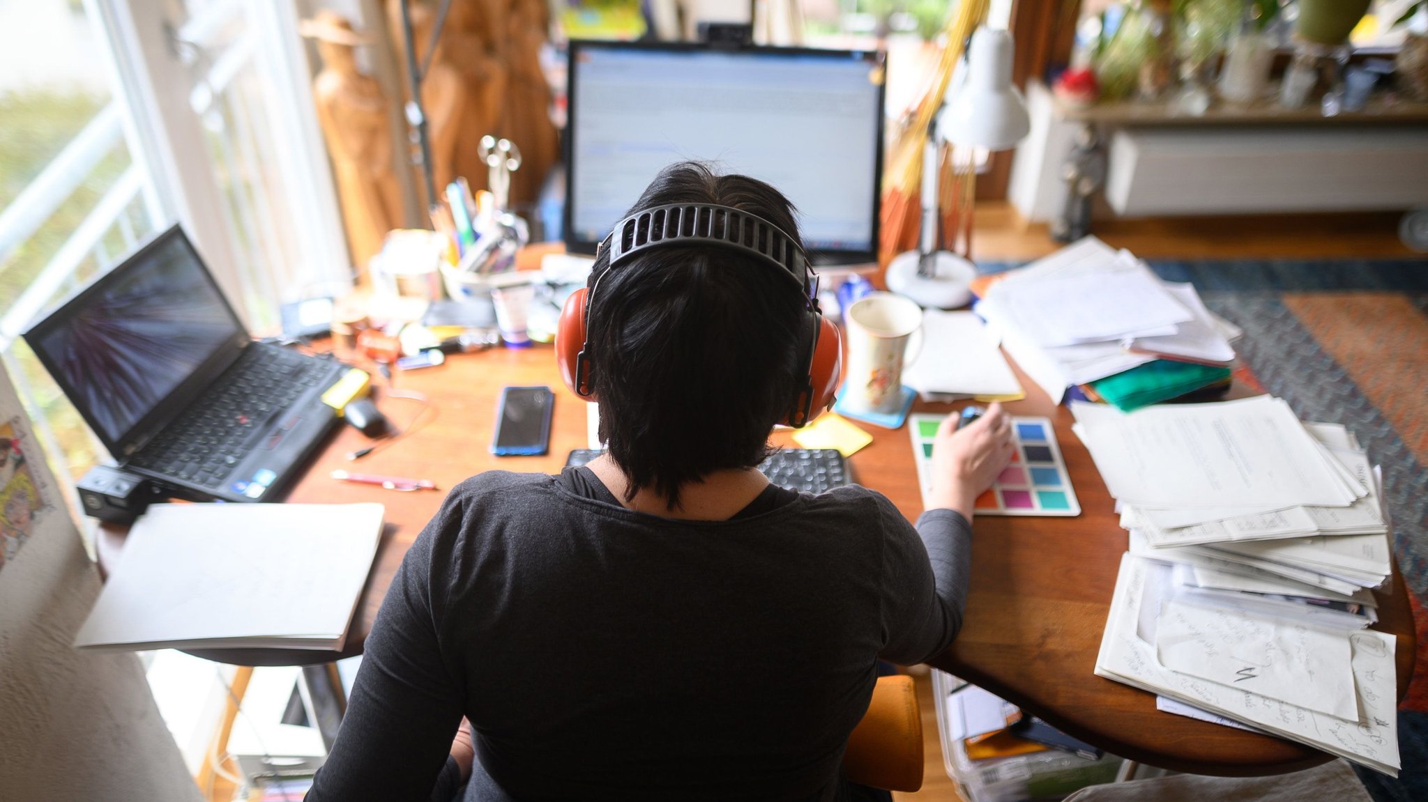 Eine Frau arbeitet mit Hörschutz im Homeoffice.