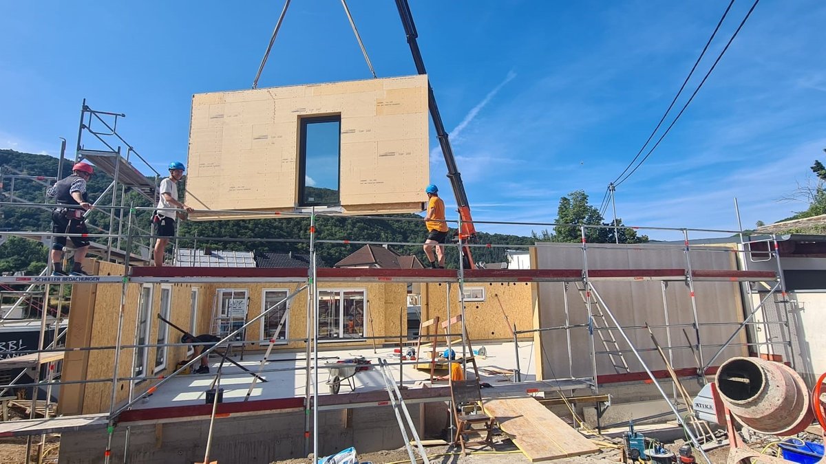 Zimmerer aus dem Landkreis Donau-Ries bauen das Freundschaftshaus im Ahrtal auf, gerade wird eine Wand mit dem Kran von oben hineingehoben. 