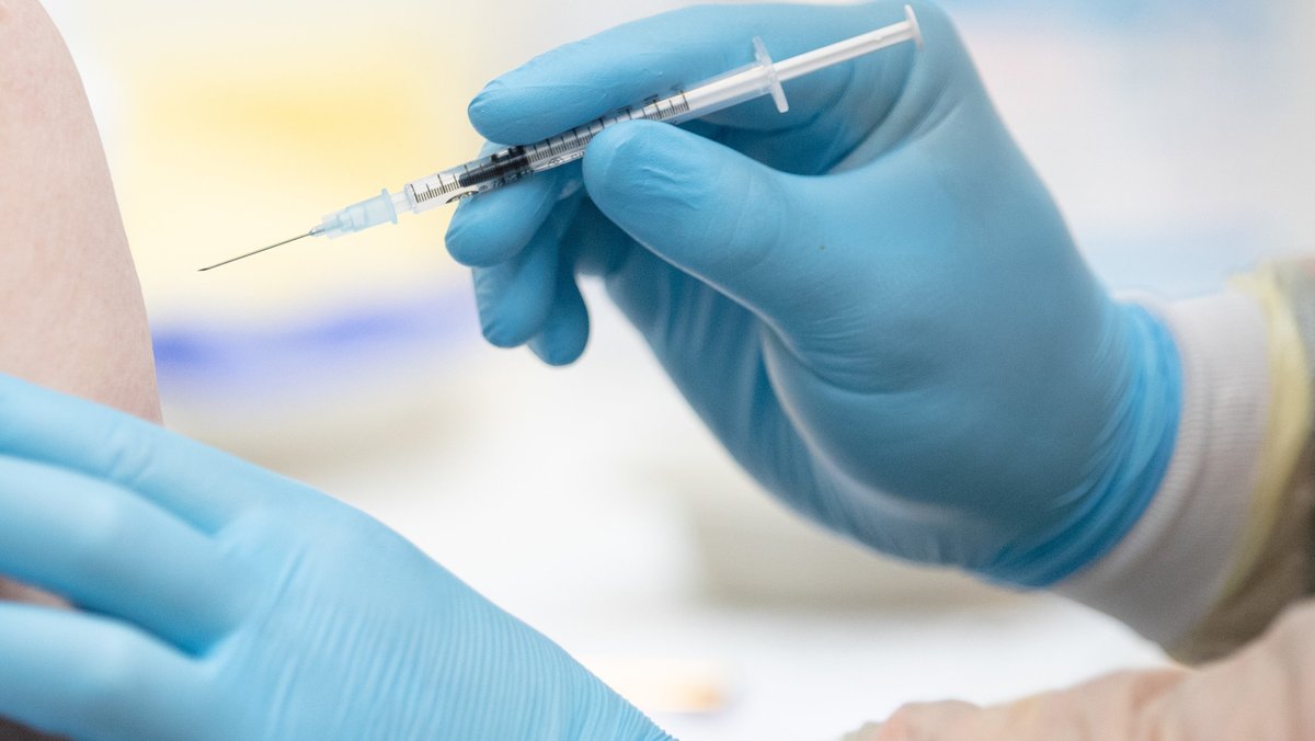 Eine Person wird im Impfzentrum von einem Notfallsanitäter des Deutschen Rotes Kreuzes mit dem Wirkstoff von Biontech/Pfizer gegen Covid-19 geimpft.