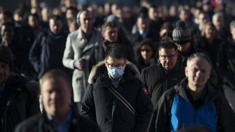 Mann mit Schutzmaske in einer Menschenmenge
