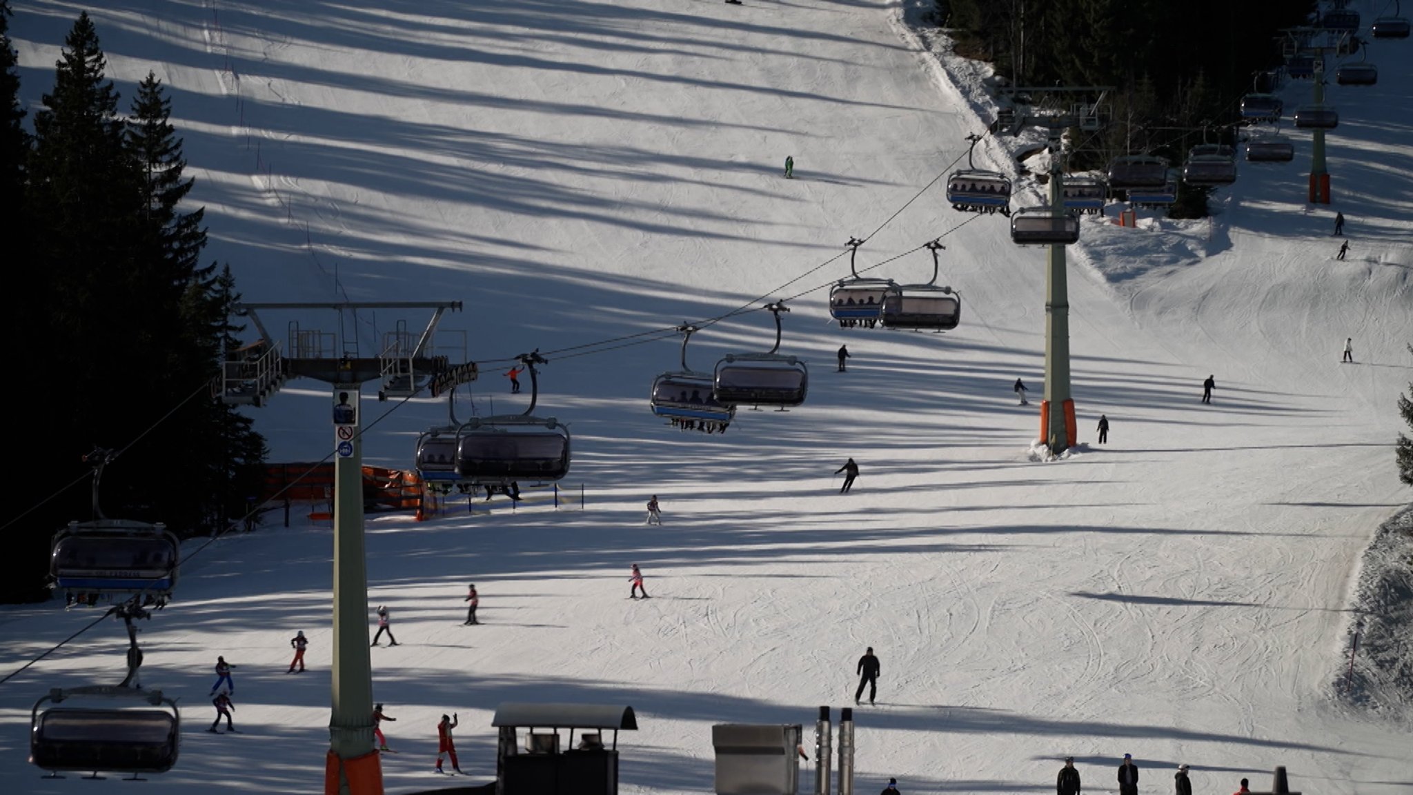 Skifahrer fahren unter einer Piste unter einer Seilbahn