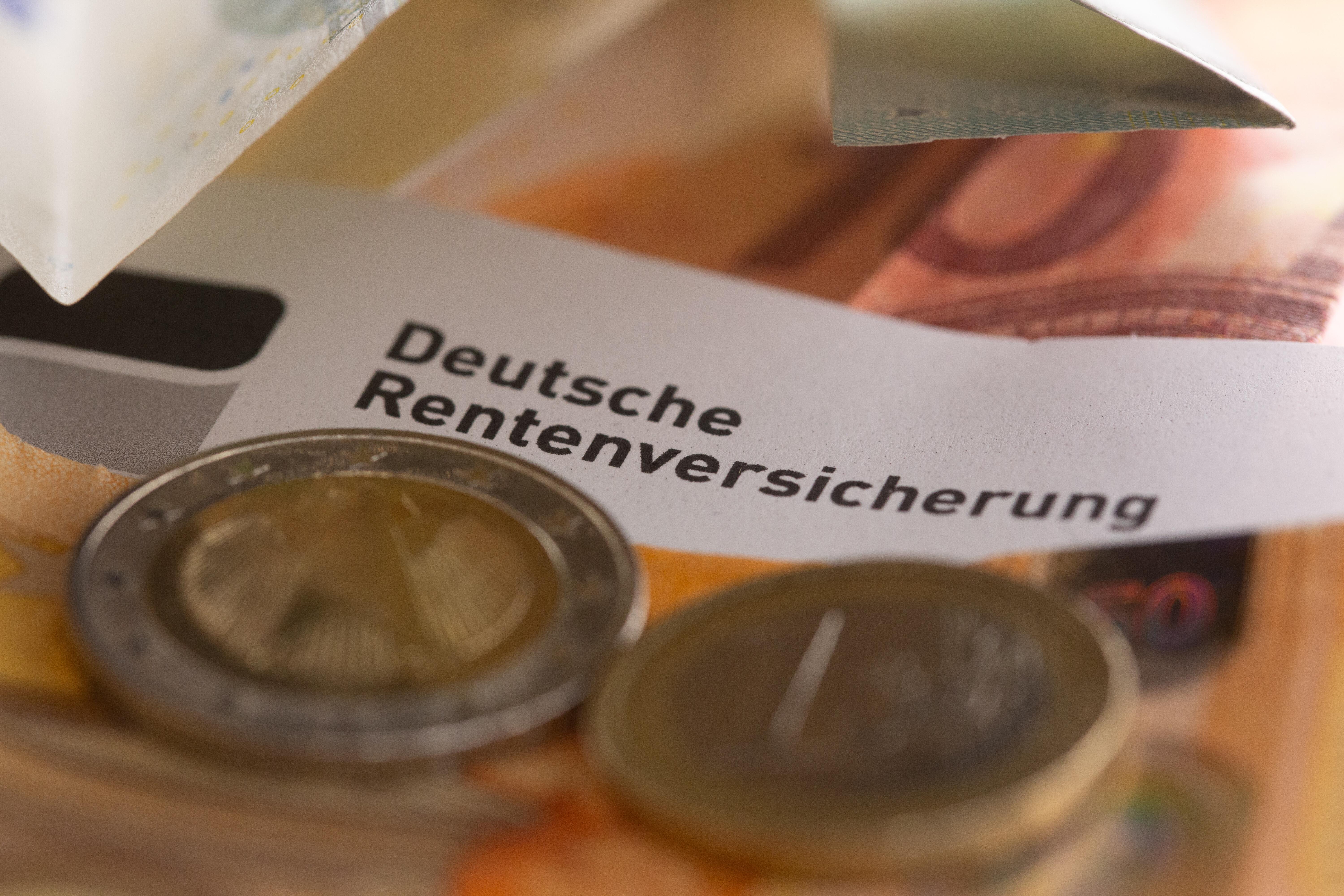 Euro-Münzen und -Banknoten liegen zusammen mit einem Rentenbescheid auf einem Tisch.