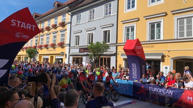 Der Start des Radrennens in der Fußgängerzone in Murnau. Links und rechts vom Start Publikum.