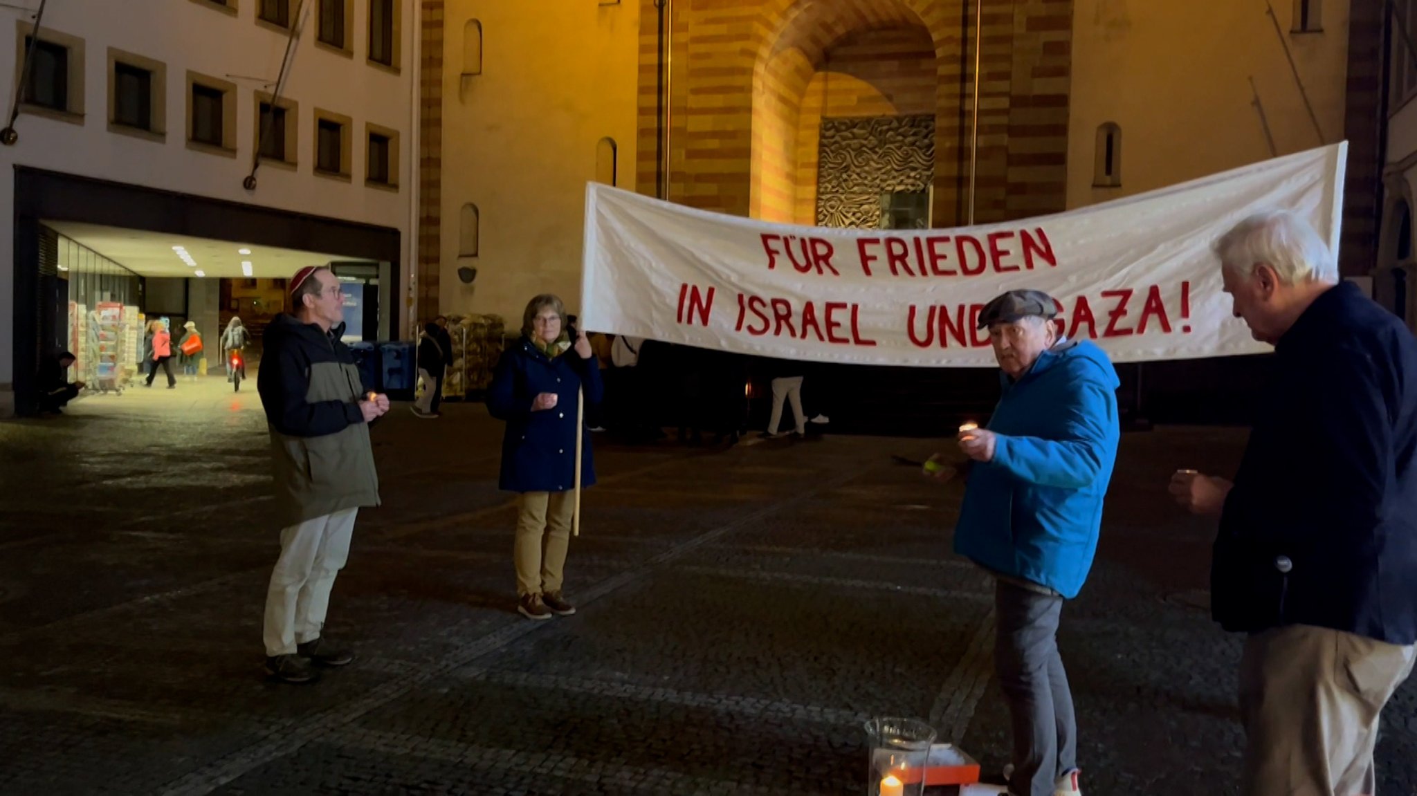 Mehrere Menschen halten ein Transparent mit der Aufschrift "Für Frieden n Israel und Gaza" hoch