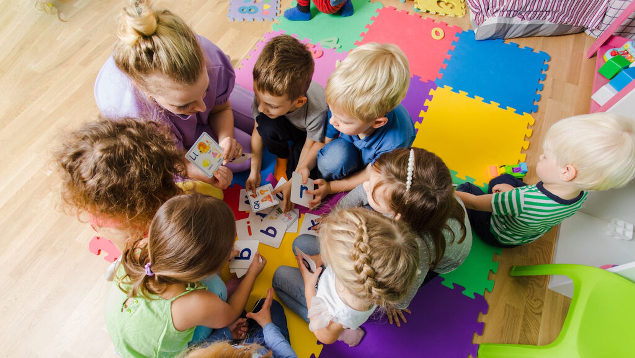 Eine Erzieherin mit einer Gruppe Kinder in einer Kindertagesstätte.