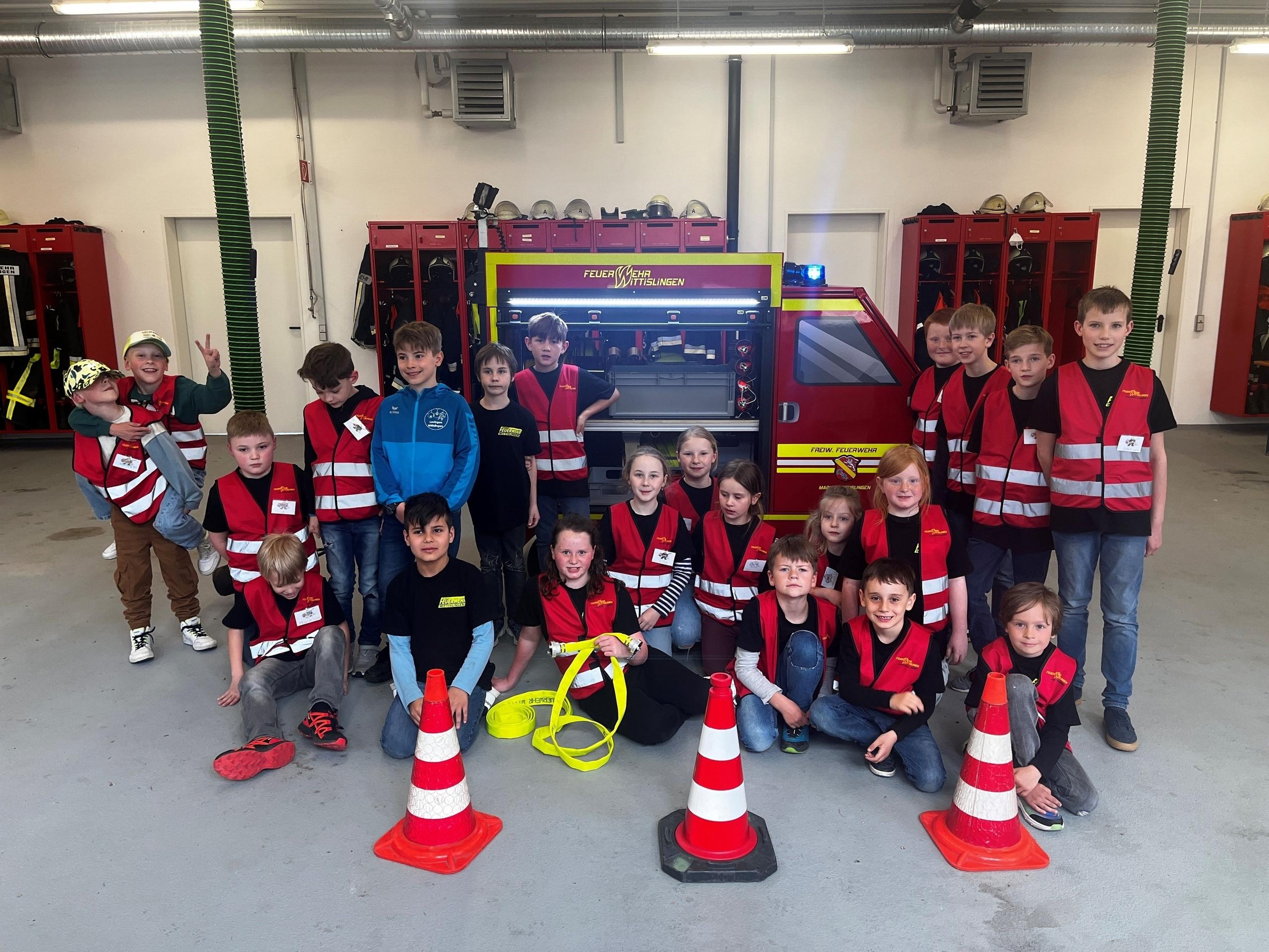 Kinder sitzen vor einem Mini-Feuerwehrauto in Wittislingen im Landkreis Dillingen