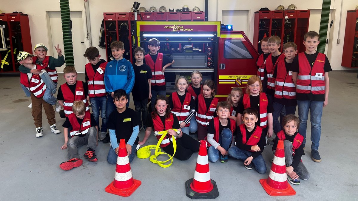 Kinder sitzen vor einem Mini-Feuerwehrauto in Wittislingen im Landkreis Dillingen