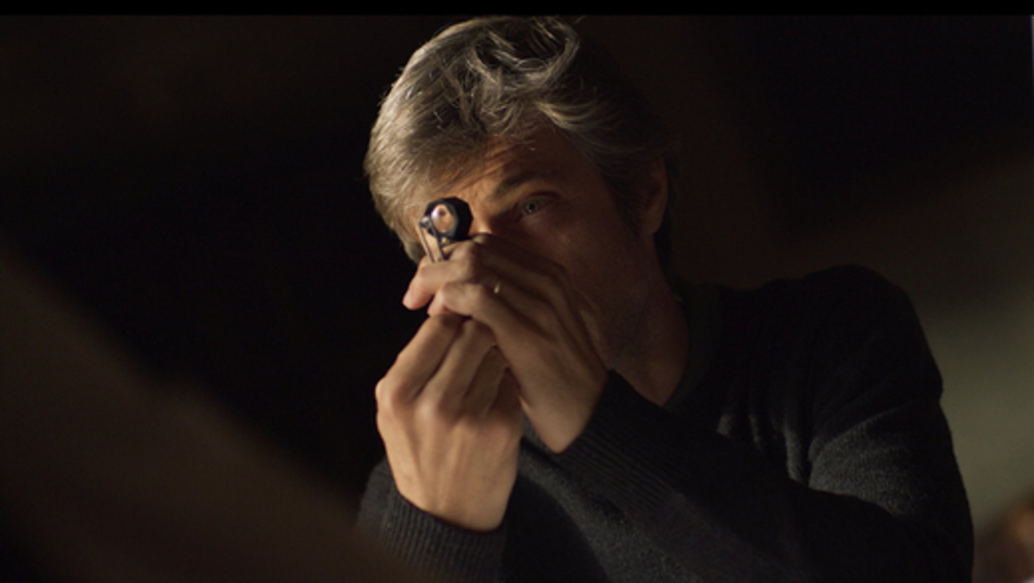 Mann begutachtet einen Diamanten durch eine Lupe