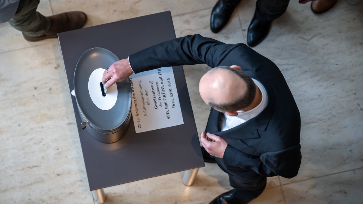 Bundeskanzler Olaf Scholz (SPD) wirft seine Stimmkarte bei der namentlichen Abstimmung über die Reform des Bundeswahlgesetzes ein.