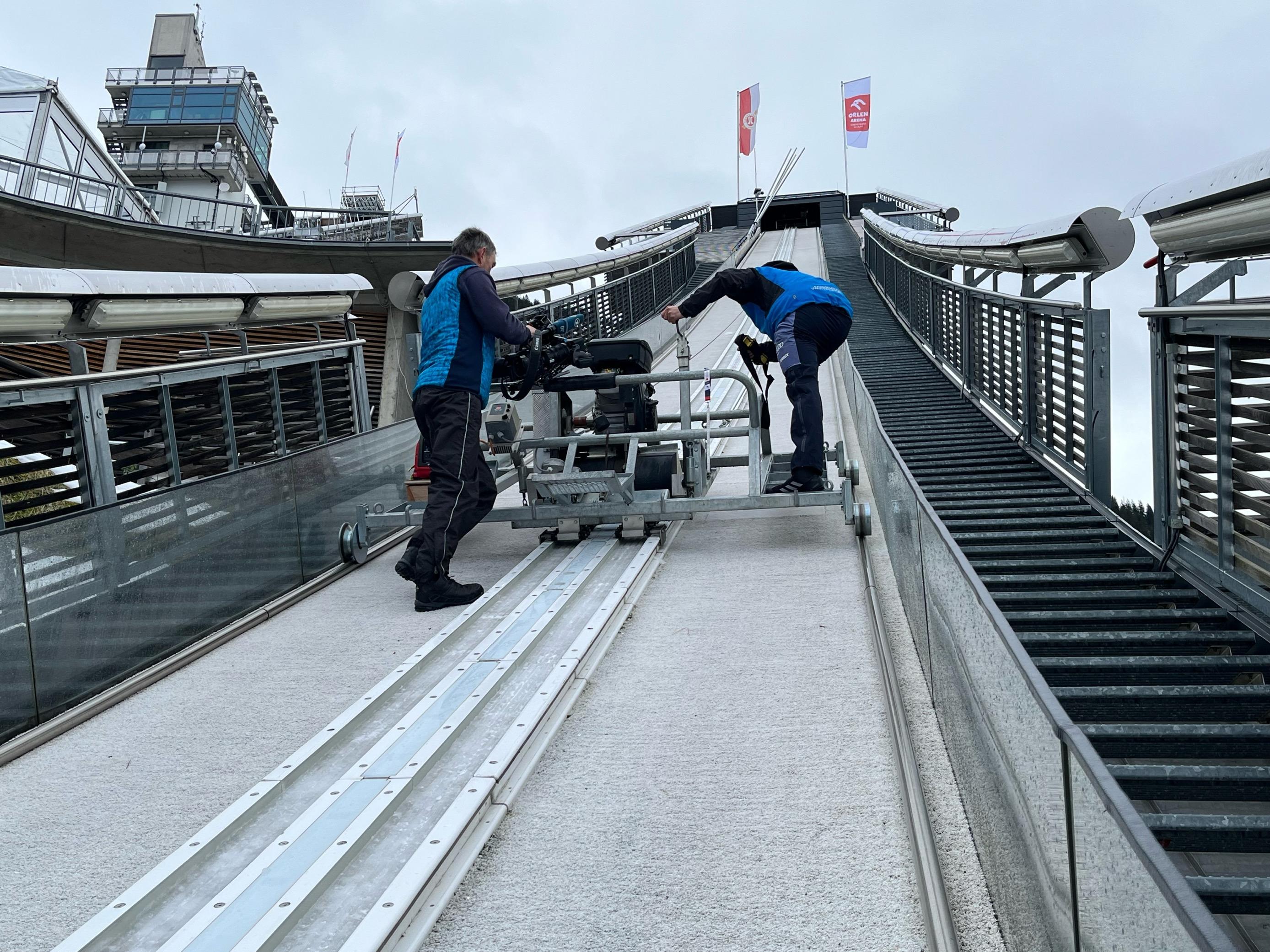 Zwei Männer präparieren die Skisprungschanzen; der BR hat sie mit der Kamera begleitet.