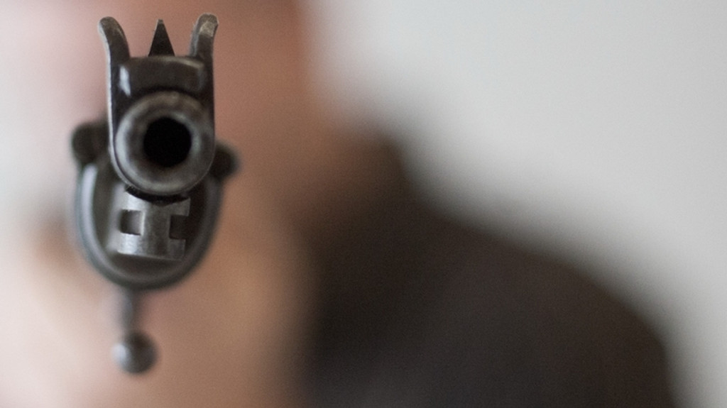 Eine Person hält eine Schusswaffe in den Händen (Symbolbild)