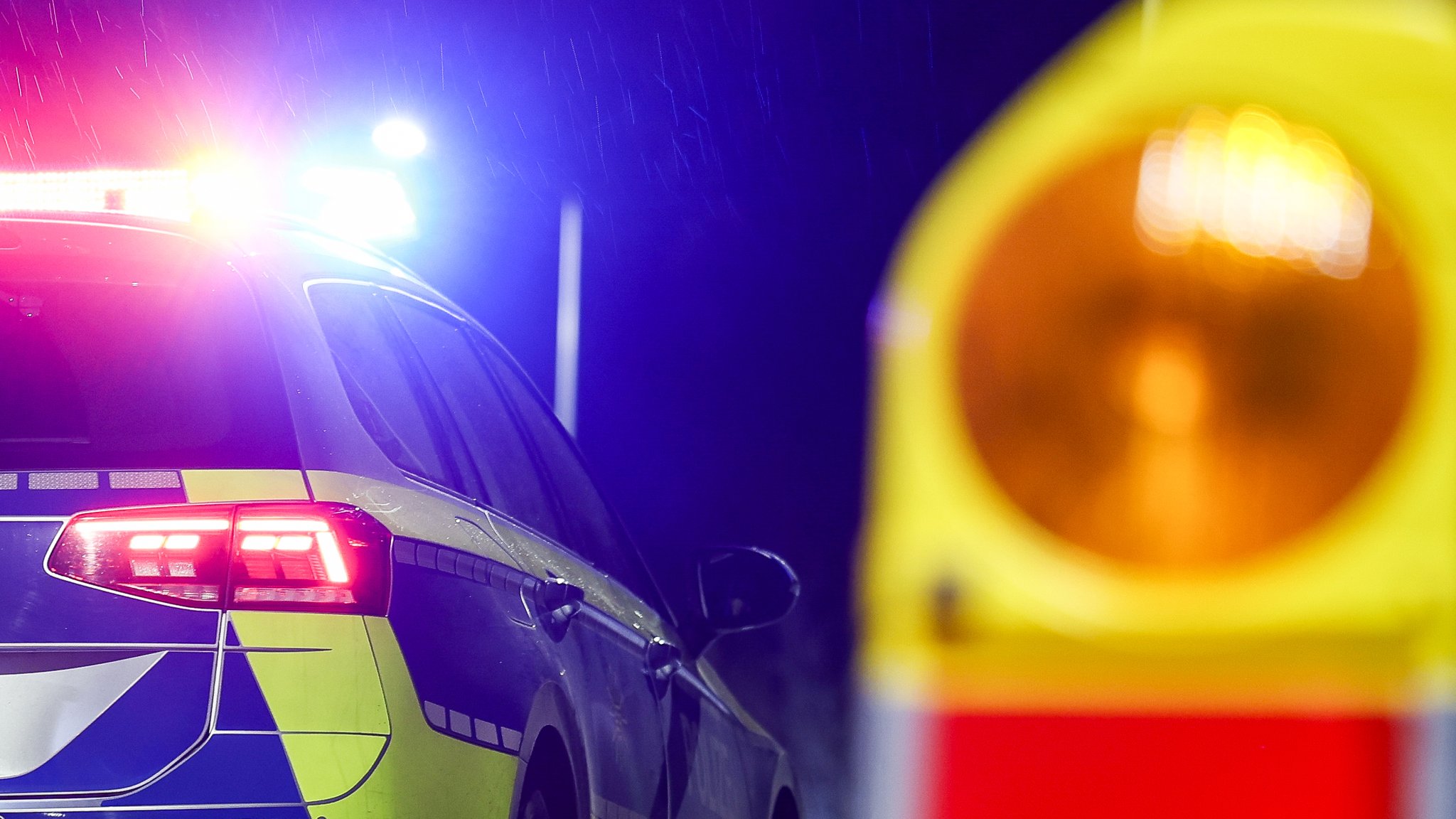 Polizeiauto mit Blaulicht und Absperrbake.