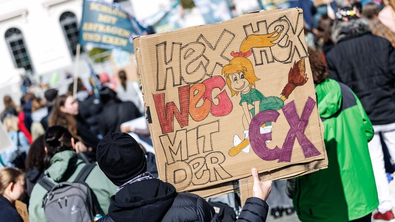 Archivbild: Ein Teilnehmer einer Demonstration steht mit einem Schild mit der Aufschrift "Hex hex, weg mit der Ex" in München | Bild: ildrechte: picture alliance/dpa|Matthias Balk Archivbild: Ein Teilnehmer einer Demonstration steht mit einem Schild mit der Aufschrift "Hex hex, weg mit der Ex" in München