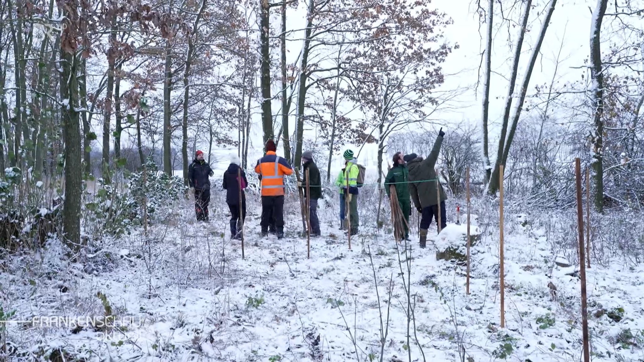 Menschen stehen in einem verschneiten Wald.