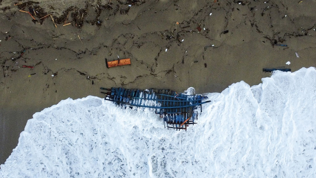 27.02.2023, Italien, Cutro: Blick auf einen Teil des Wracks eines gekenterten Bootes, das an einem Strand angeschwemmt wurde. Rettungskräfte suchten zu Wasser und aus der Luft weiter nach Dutzenden von Menschen, die nach einem Schiffsunglück vor der süditalienischen Küste noch immer vermisst werden. Bei dem Unglück waren zahlreiche Menschen ums Leben gekommen. Foto: Luigi Navarra/AP/dpa +++ dpa-Bildfunk +++