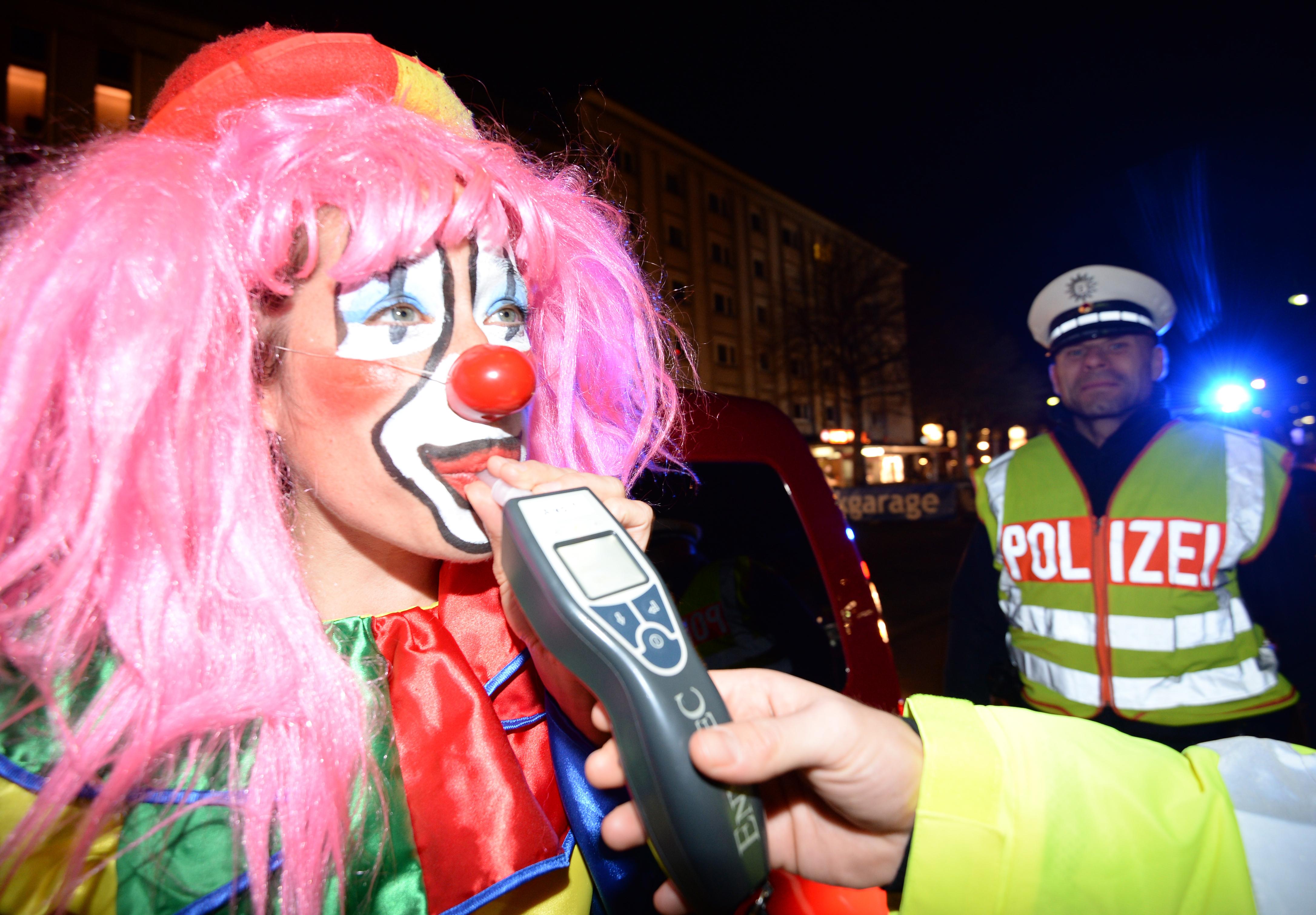 Ein Clown mit pinker Perücke muss in einer Polizeikontrolle in ein Röhrchen pusten