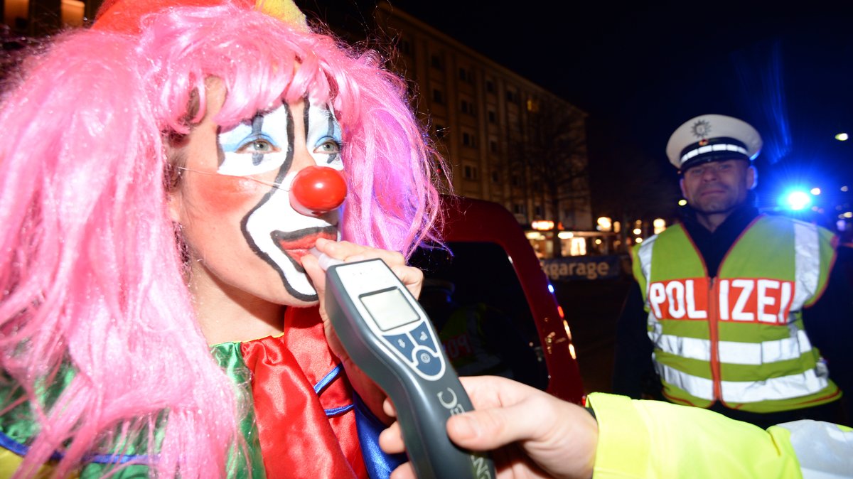 Ein Clown mit pinker Perücke muss in einer Polizeikontrolle in ein Röhrchen pusten