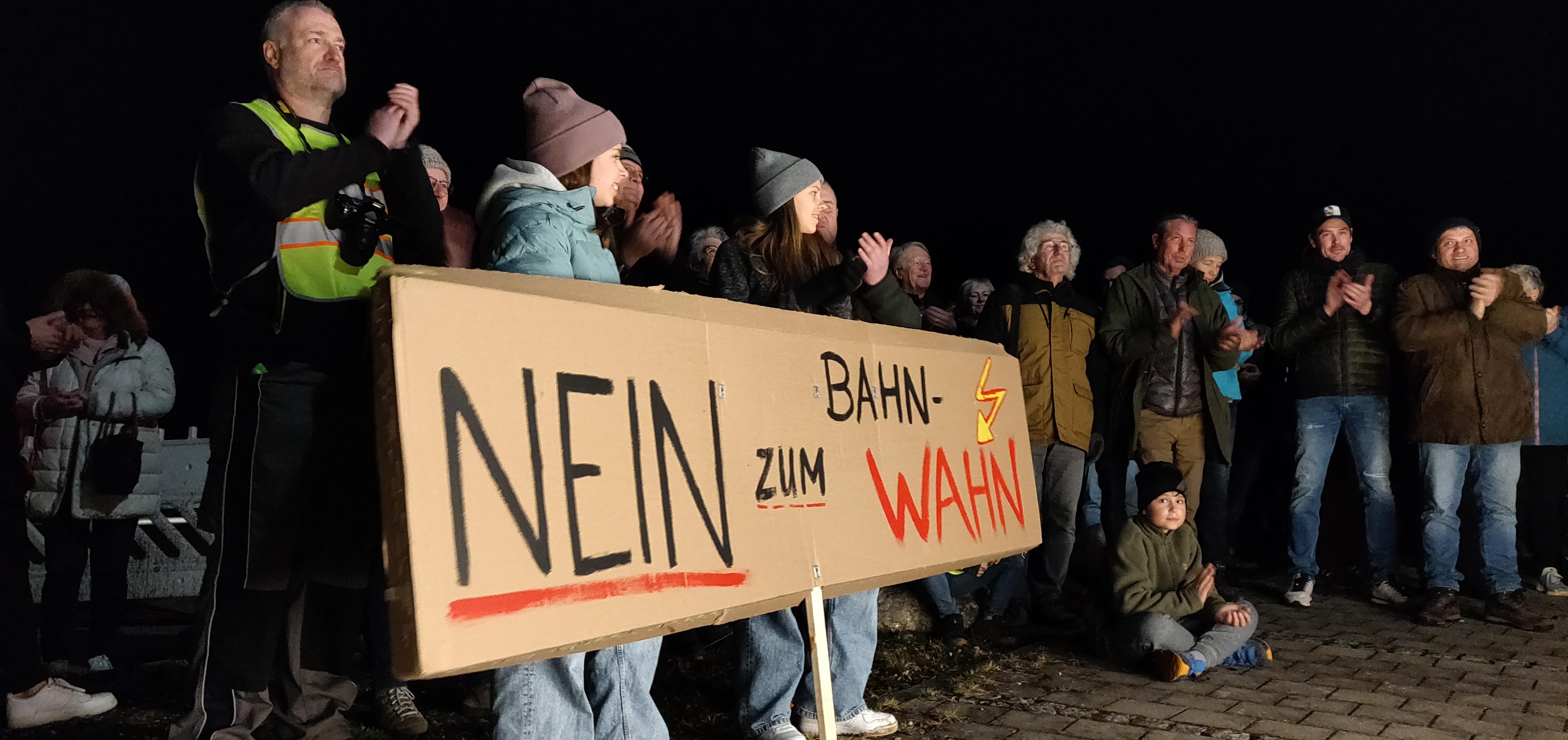 Teilnehmer einer Kundgebung gegen die geplante Bahn-Trasse bei Adelsried mit Transparent "Nein zum Bahn-Wahn"