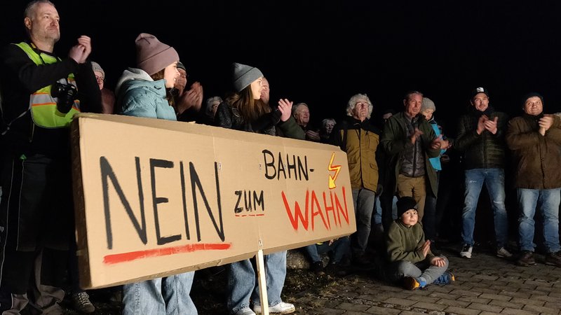 Teilnehmer einer Kundgebung gegen die geplante Bahn-Trasse bei Adelsried mit Transparent "Nein zum Bahn-Wahn"