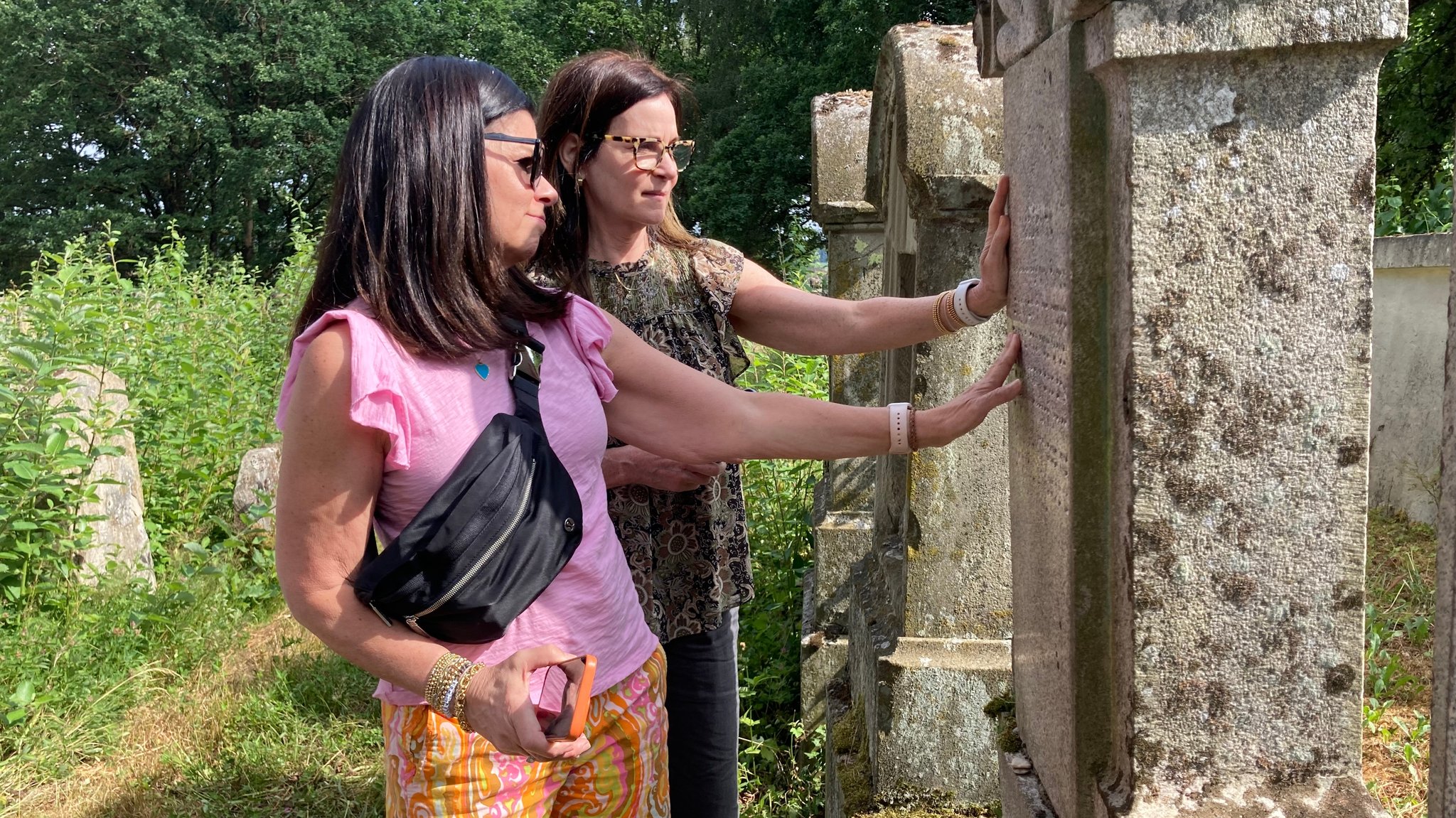 Lisbeth Herer und ihre Schwester Karen Belt berühren den Grabstein ihres Ur-Ur-Großvaters Samuel Schloss in Bechhofen.