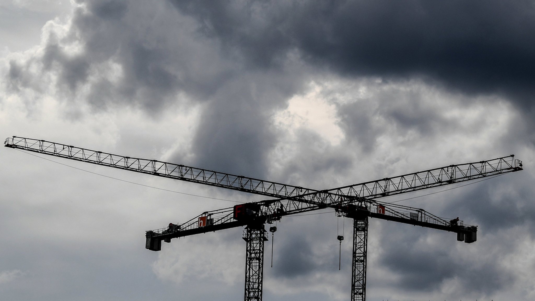 Baukräne sind vor dunklen Wolken zu sehen.