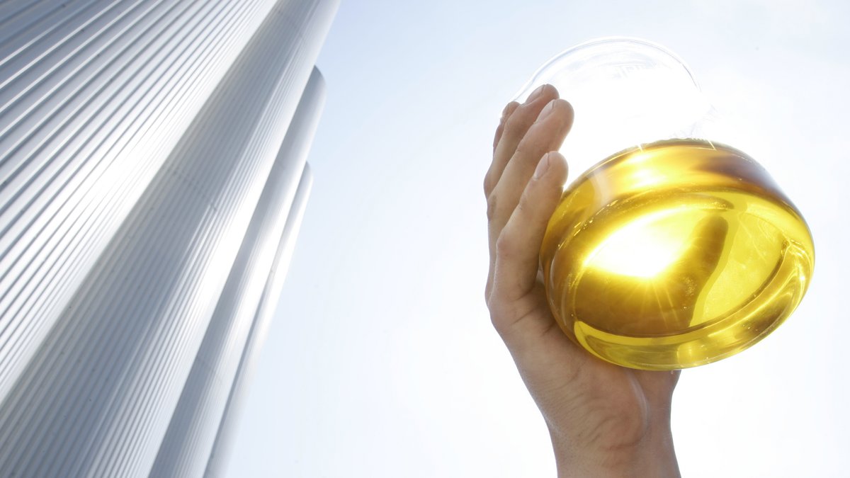 Rapsöl in einem Glasbehälter vor dem Hintergrund einer Biodiesel-Anlage