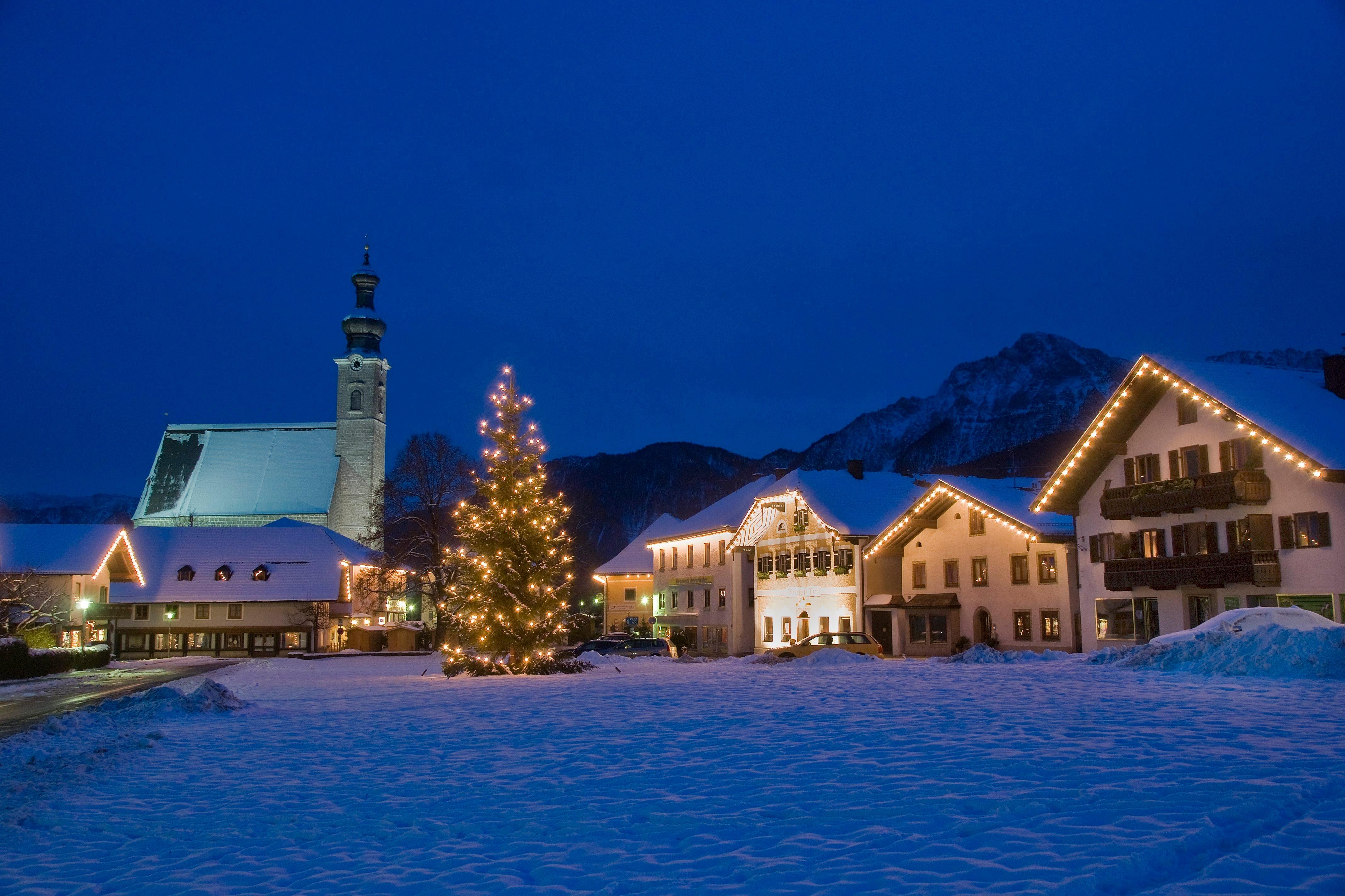 Weihnachtlich beleuchteter Dorfplatz des Ortes Anger mit Christbaum. Im Hintergrund der Berg Hochstaufen. Berchtesgadener Land, Rupertiwinkel, Oberbayern.