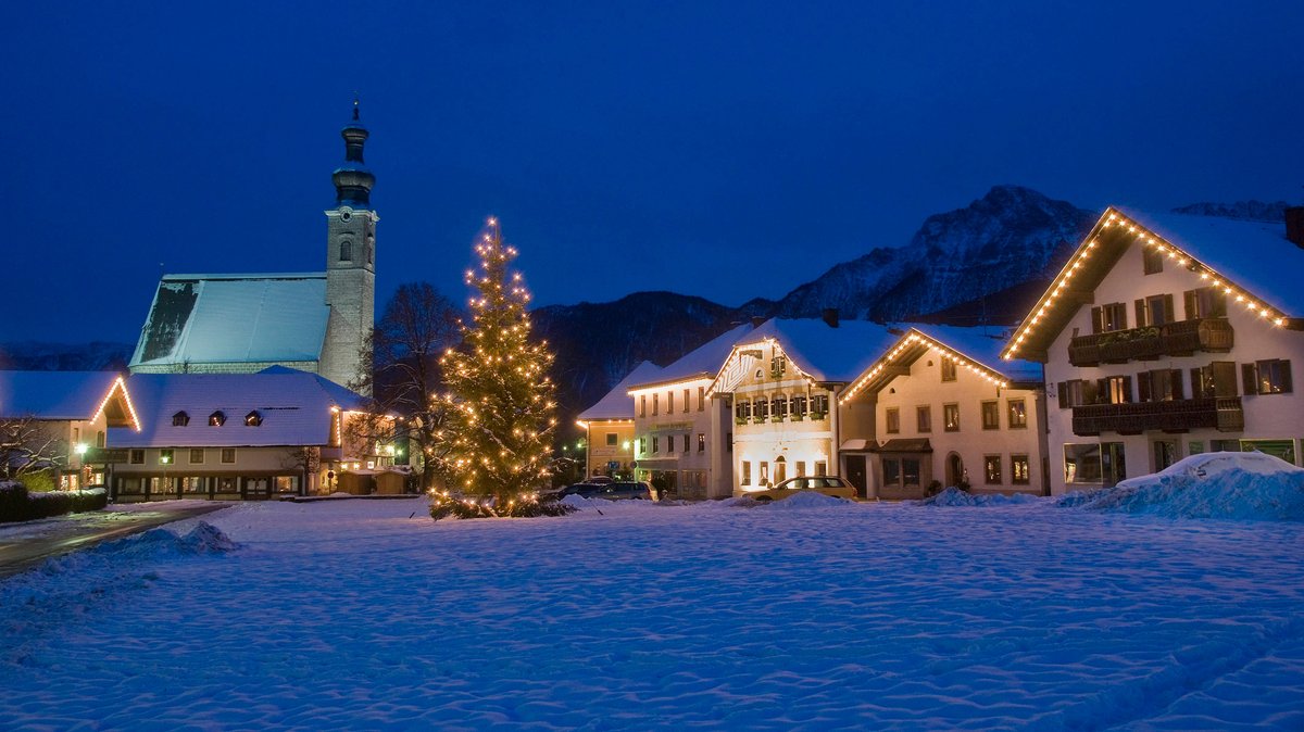 Weihnachtlich beleuchteter Dorfplatz des Ortes Anger mit Christbaum. Im Hintergrund der Berg Hochstaufen. Berchtesgadener Land, Rupertiwinkel, Oberbayern.