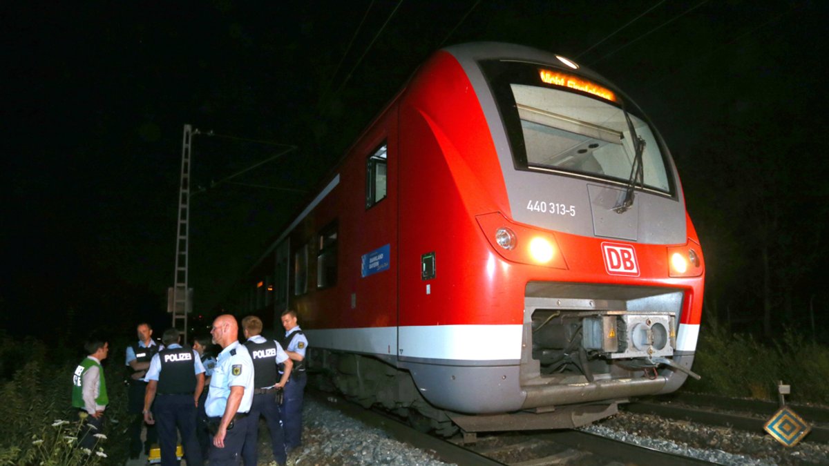 Polizisten stehen in Würzburg neben einem Regionalzug, in dem ein 17-jähriger Afghane mit Axt und Messer Passagiere attackiert hat.