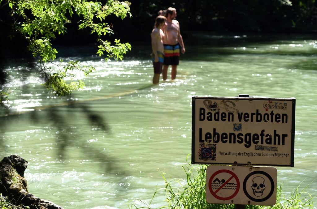 ARCHIV - 06.06.2015, Bayern, München: Ein Schild mit der Aufschrift «Baden verboten Lebensgefahr» steht am 07.06.2015 am Ufer des Eisbachs im Englischen Garten in München (Bayern). Warme Temperaturen und blauer Himmel bestimmen das Wetter in der Landeshauptstadt. Foto\ Felix Hörhager/dpa +++(c) dpa - Bildfunk+++ (zu dpa: «Polizei: Leiche im Eisbach ist wohl vermisster Student») Foto: Felix Hörhager/dpa +++ dpa-Bildfunk +++