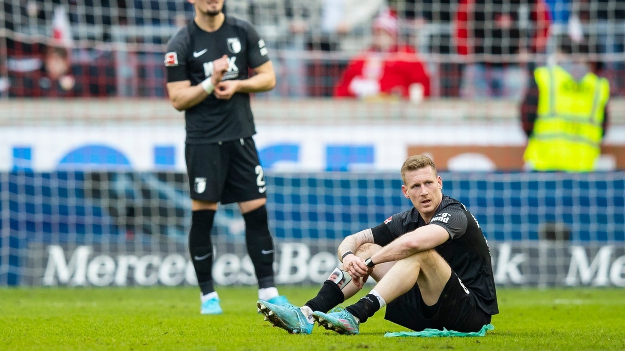 Augsburgs Andi Zeqiri (l) und Augsburgs Andre Hahn (r) stehen und sitzen nach dem Schlusspfiff auf dem Platz. 