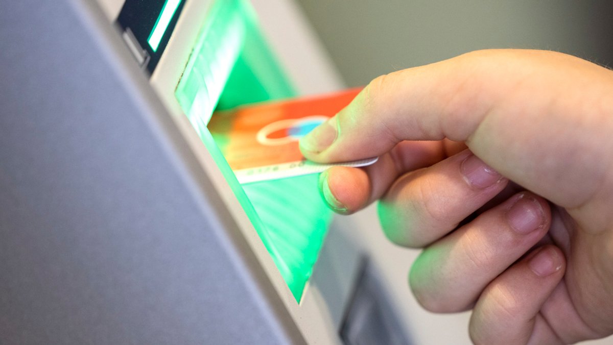 Jemand steckt eine EC-Karte in einen Geldautomaten, um Bargeld abzuheben.