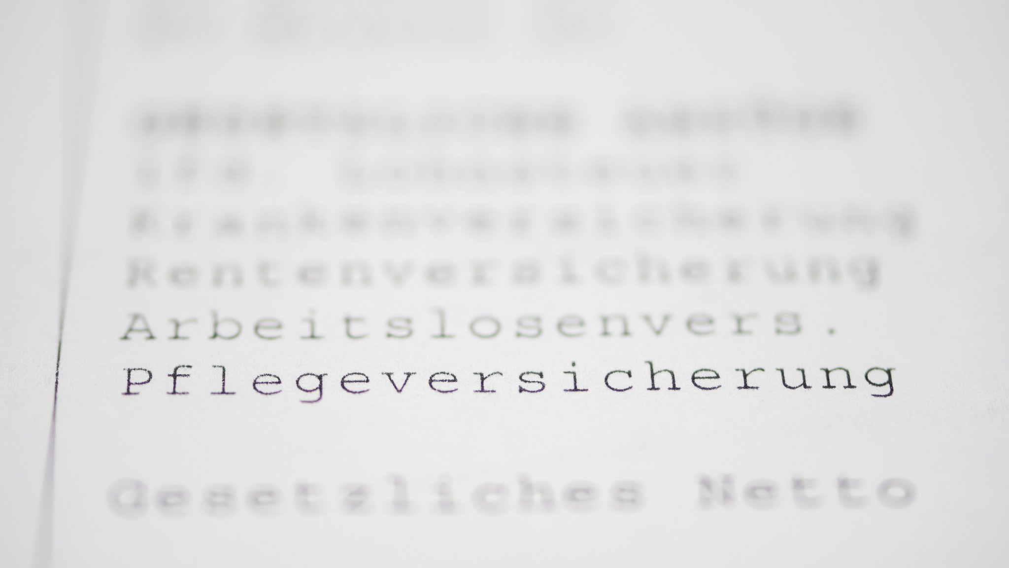(Symbolbild) Auf einem weißen Blatt Papier steht das Wort "Pflegeversicherung".